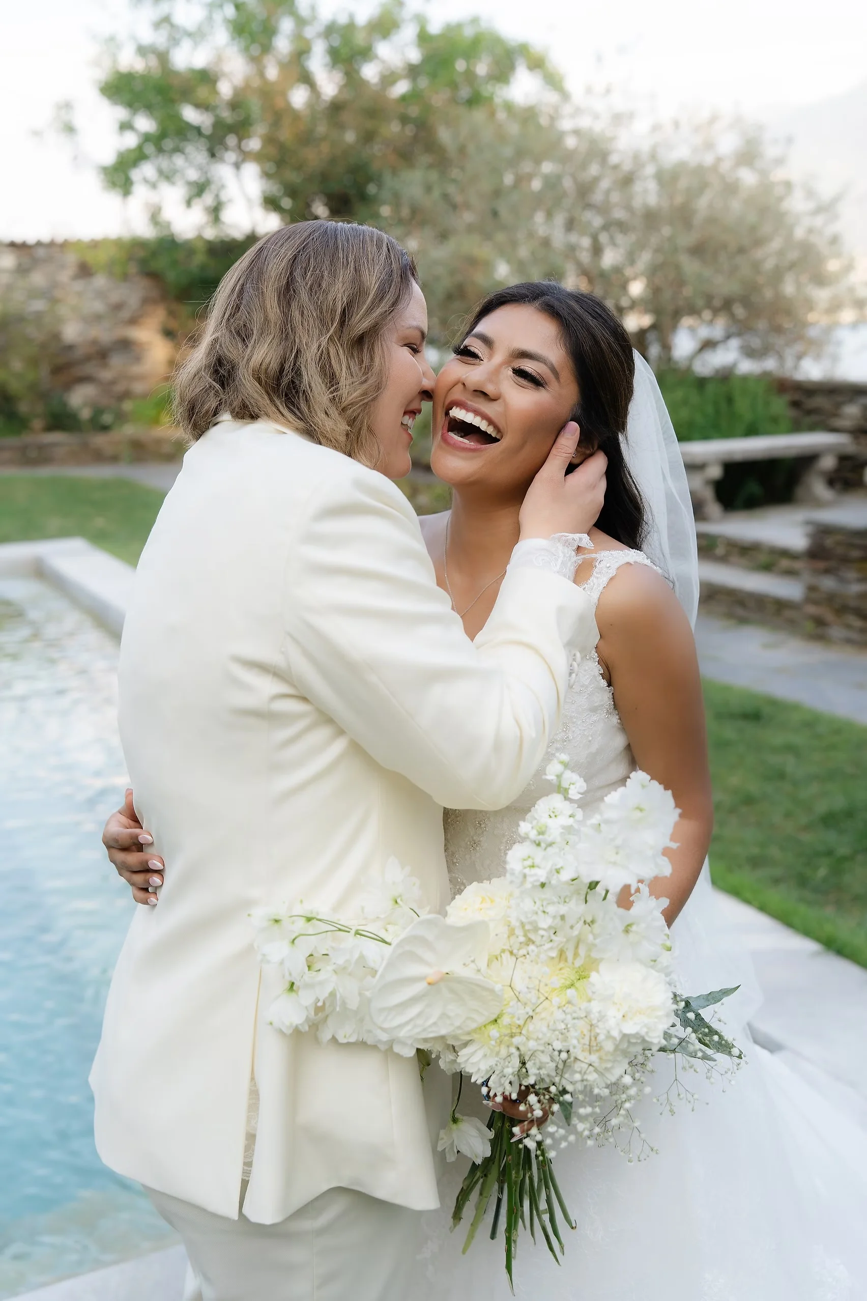 Ashley Rodriguez-Vargas and Dionne Vargas laugh and embrace near a pool at Villa Emden on Brissago Island, Switzerland.