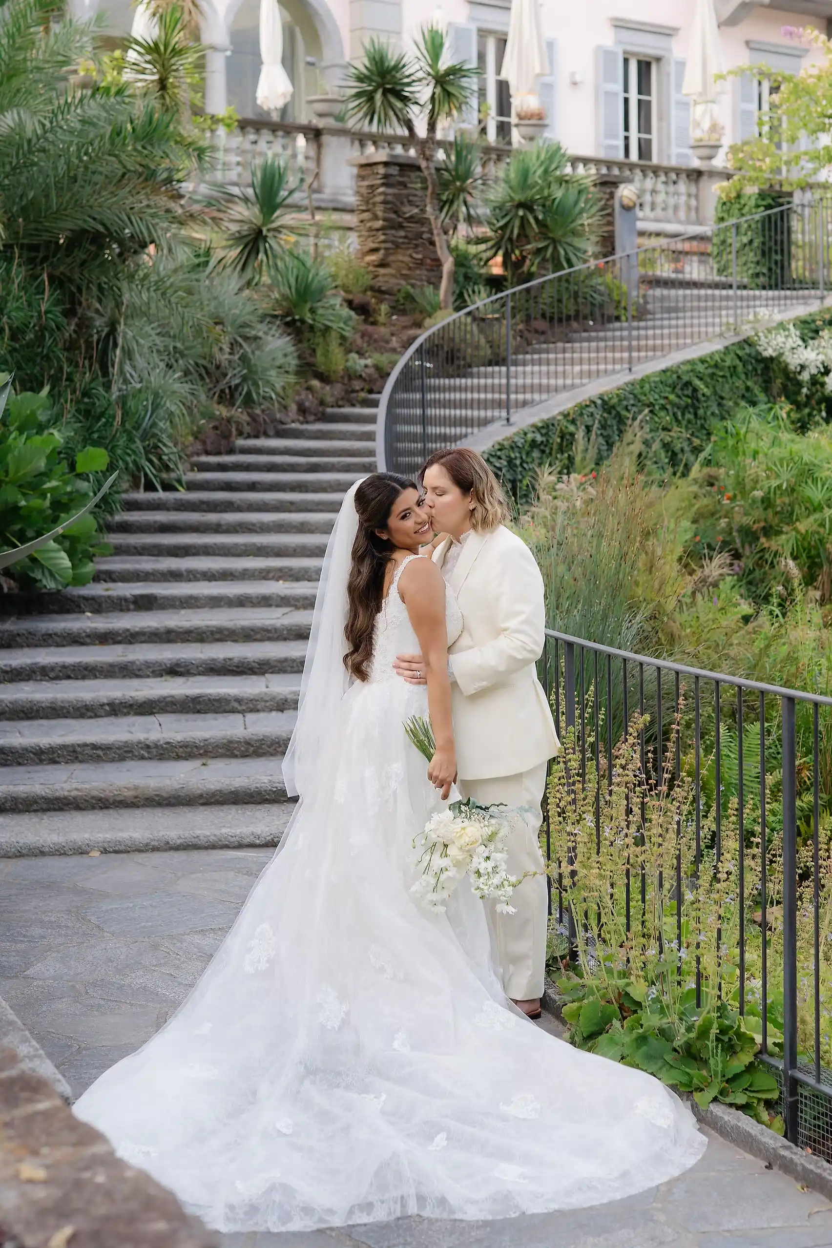 Ashley Rodriguez-Vargas and Dionne Vargas embrace on stone steps at Villa Emden on Brissago Island, Switzerland.