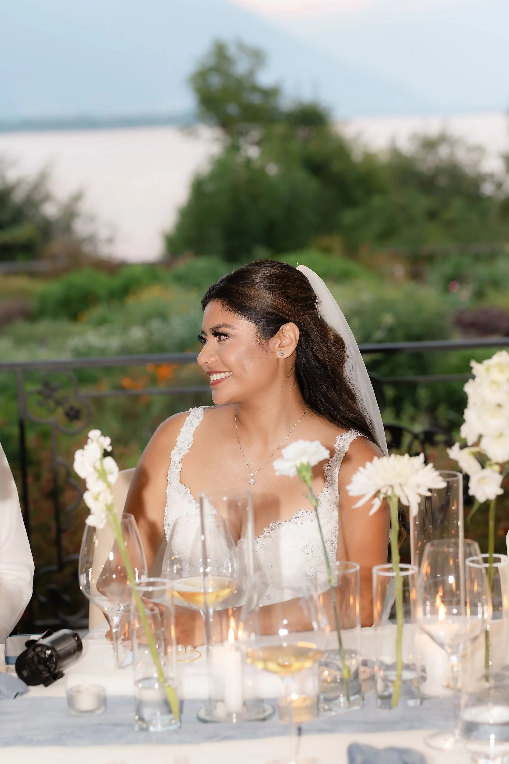 Bride Ashley Rodriguez-Vargas smiles at the sweetheart table during the reception at Villa Emden on Brissago Island, Switzerland.