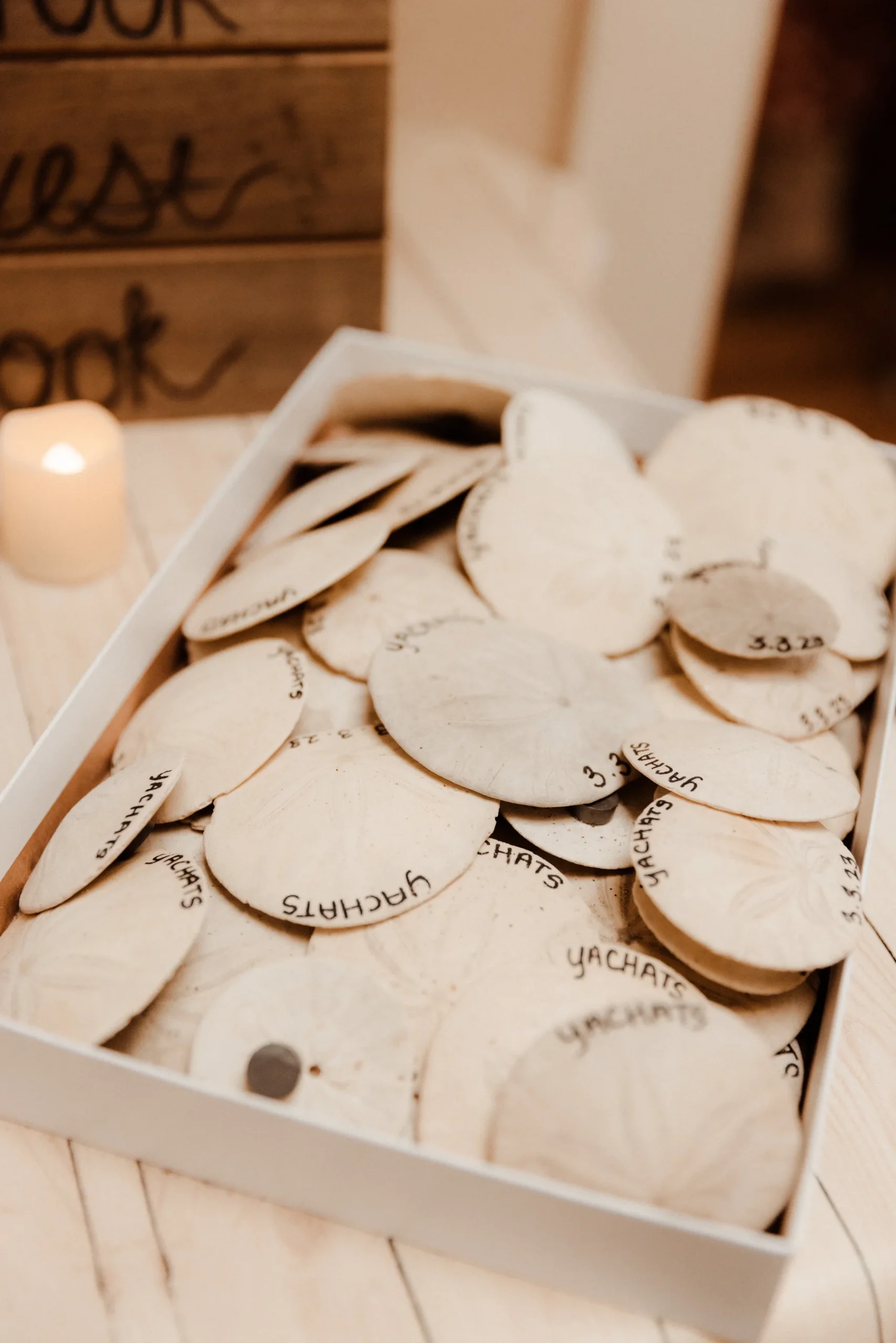 Wooden disc guest book tokens inscribed with 'Yachats' and date 3.8.23 fill a white box at Yachats Inn.
