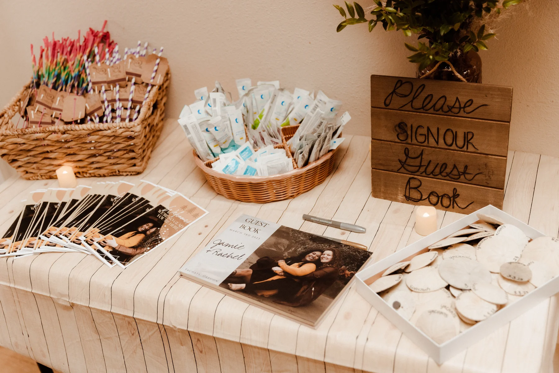 Guest book table at Rachel and Jamie Snow's wedding at Yachats Inn in Yachats, Oregon, with wooden sign, photo book, and favors.