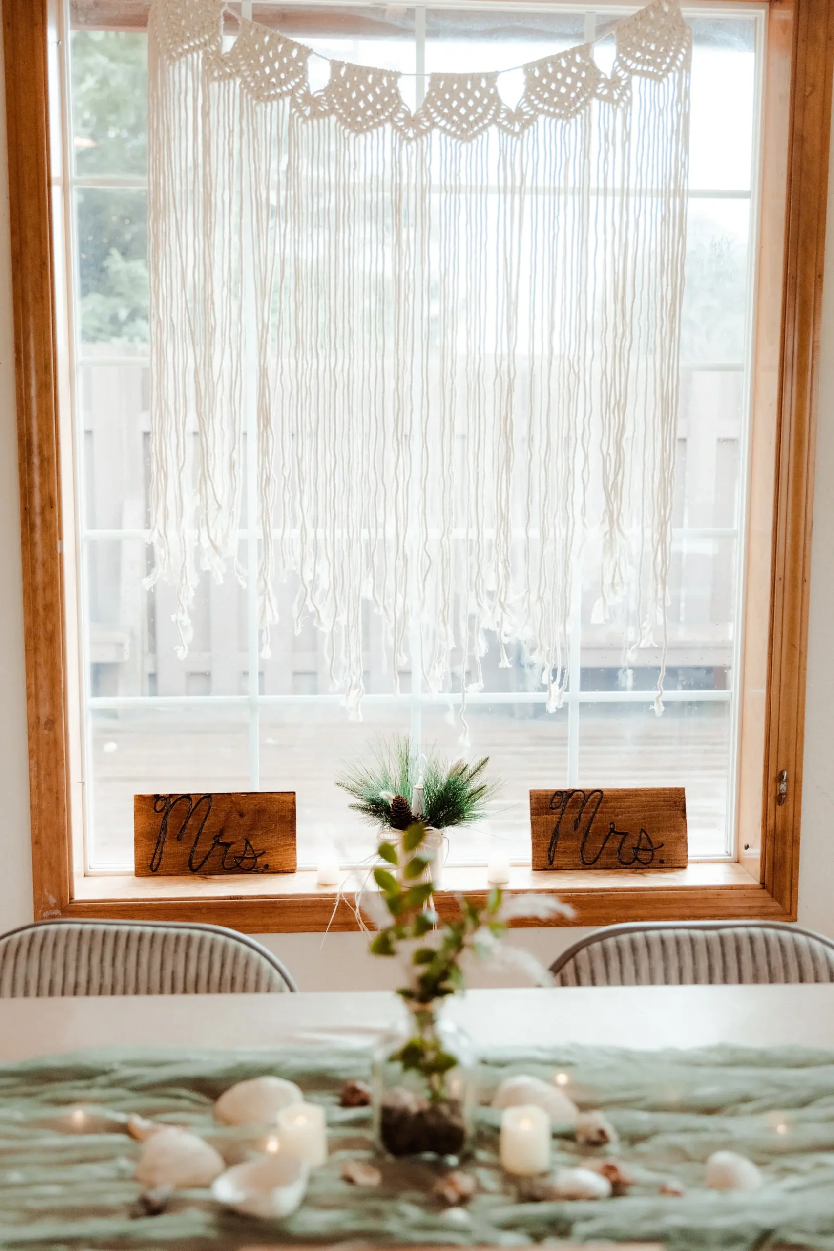 Mrs. and Mrs. wooden signs flank a pine centerpiece on the windowsill at Yachats Inn during Rachel and Jamie Snow's wedding reception.