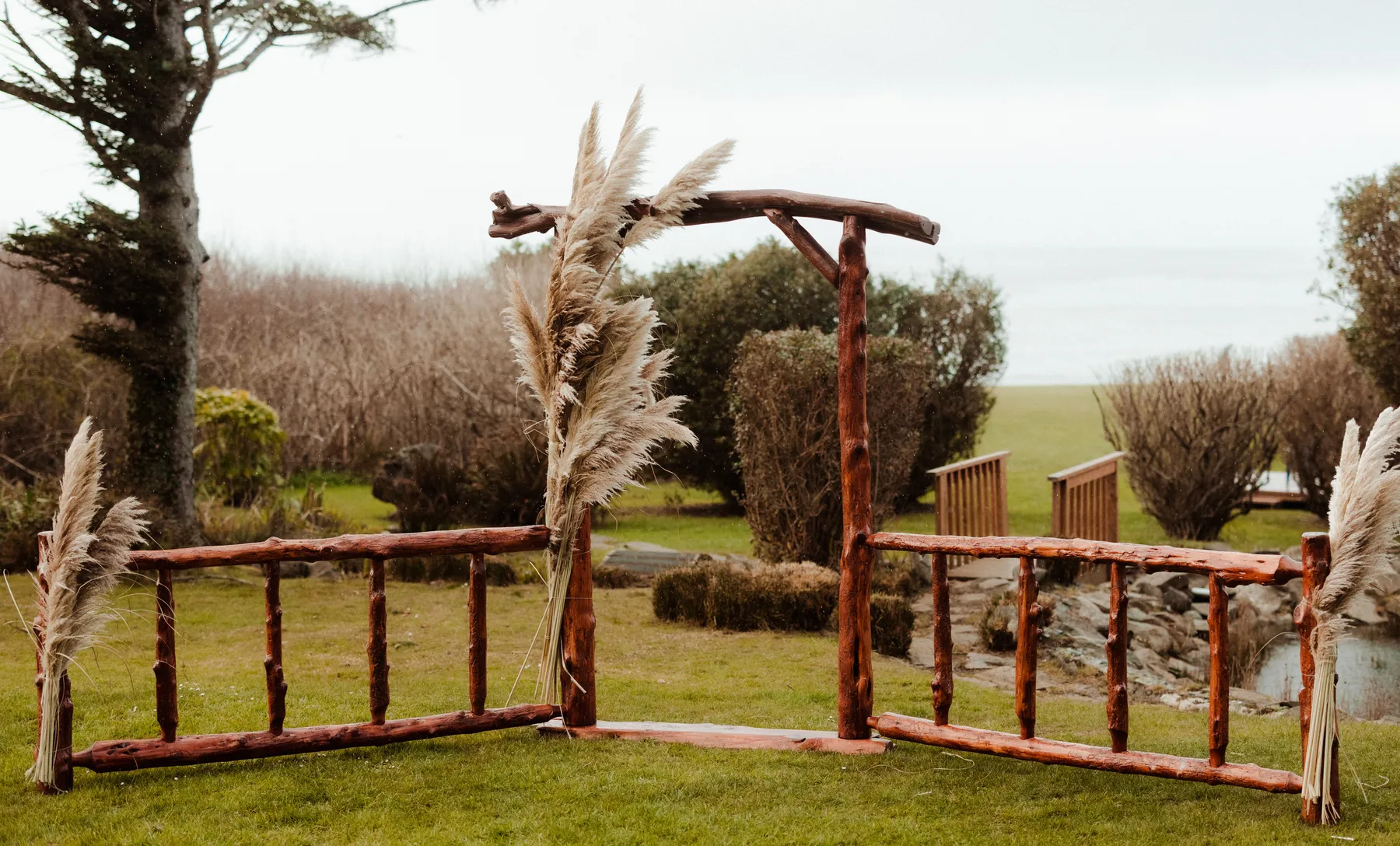 Rustic wooden arch with pampas grass at Yachats Inn in Yachats, Oregon, for Rachel and Jamie Snow's wedding.