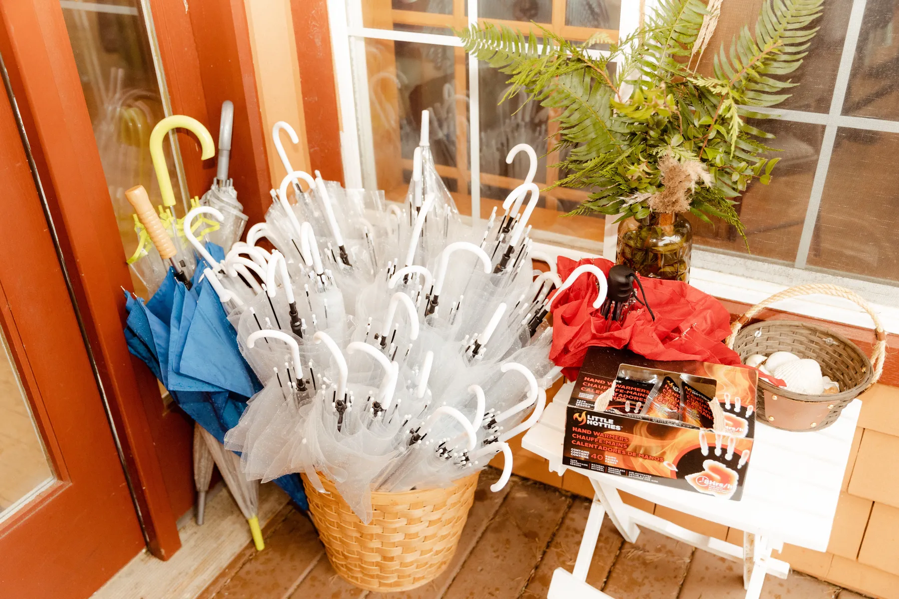 Clear and blue umbrellas in wicker baskets with Little Hotties hand warmers on a porch at Yachats Inn, Oregon.