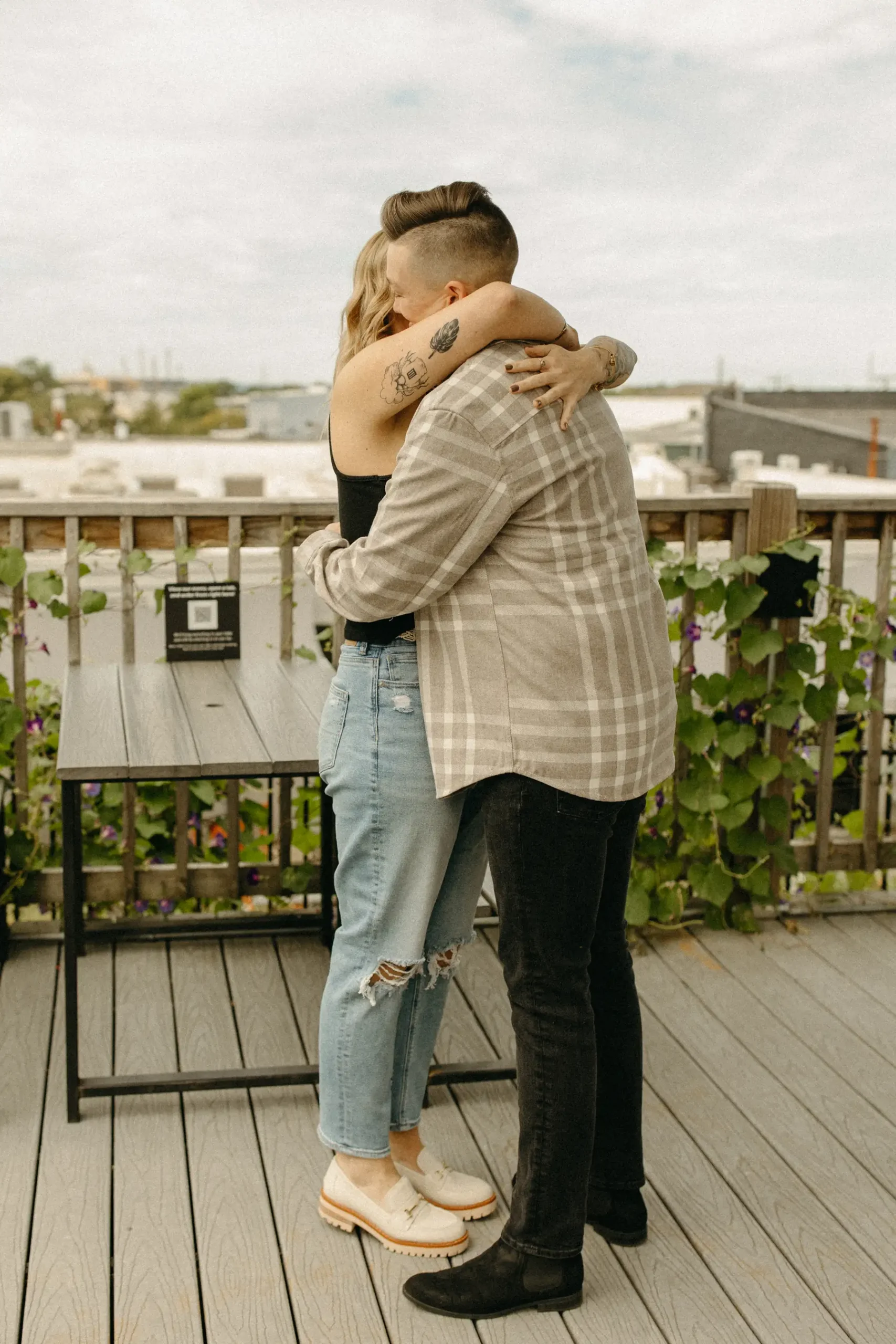 The couple shares a close embrace on a rooftop deck at Gravely Brewing Co in Denver, Colorado.