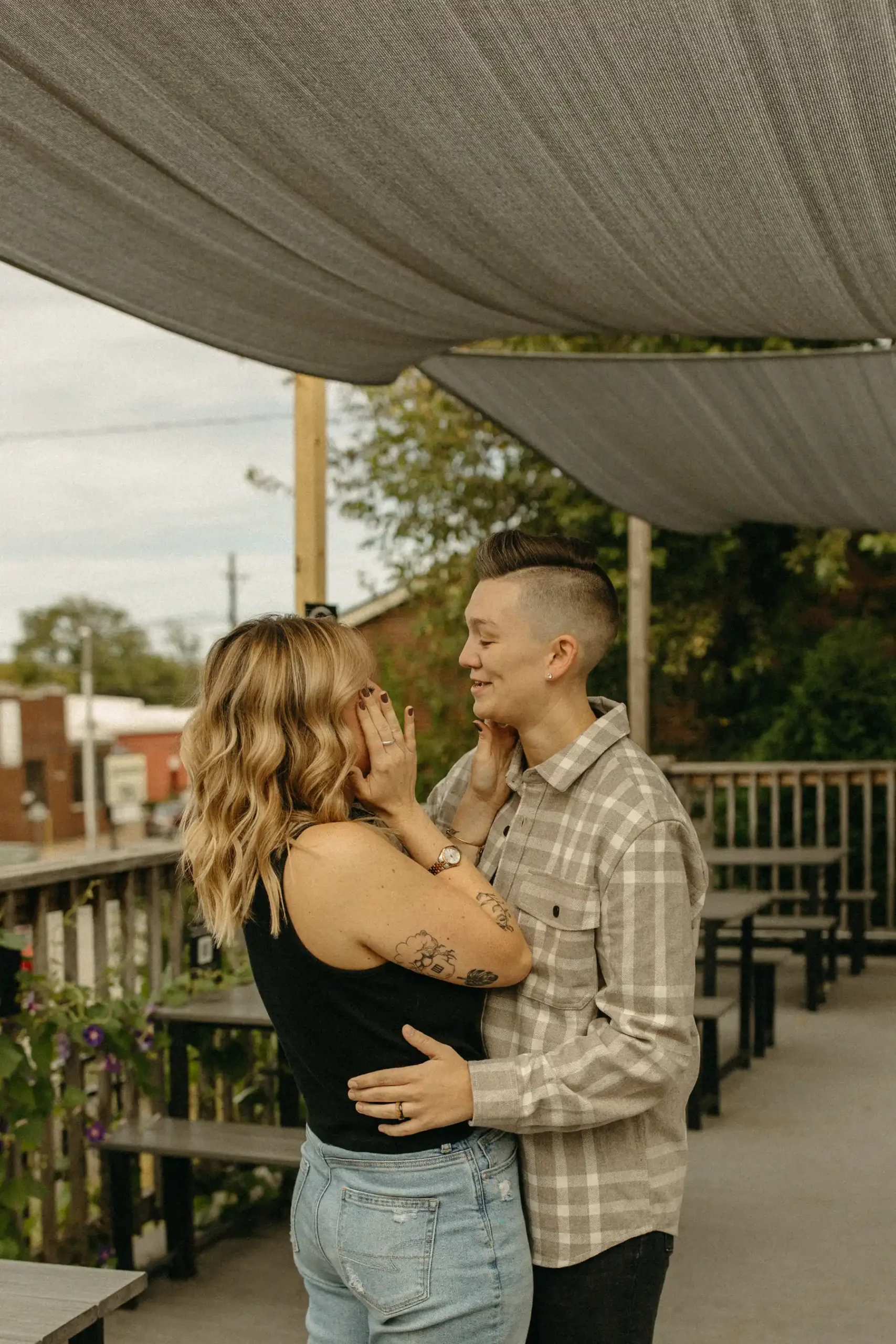 The couple embraces and gazes at each other under a canvas canopy on the patio at Gravely Brewing Co in Denver, Colorado.