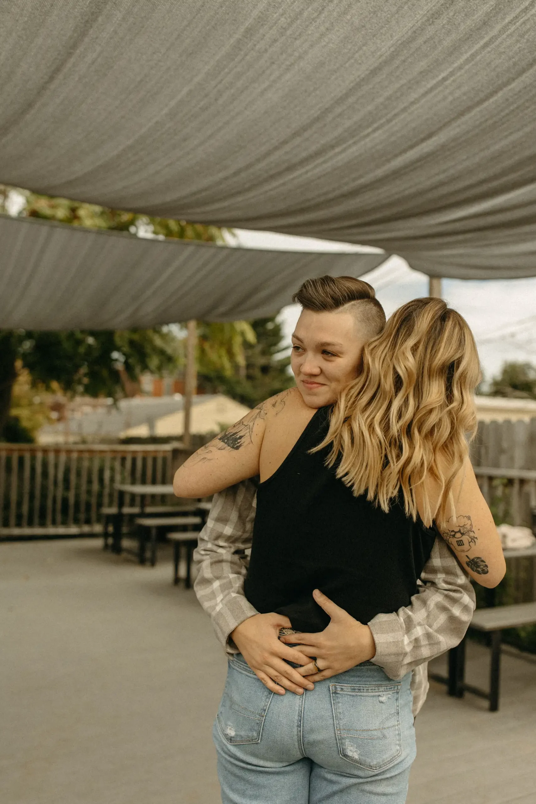 The couple embraces and shares a tender moment under a shade sail at Gravely Brewing Co in Denver, Colorado.