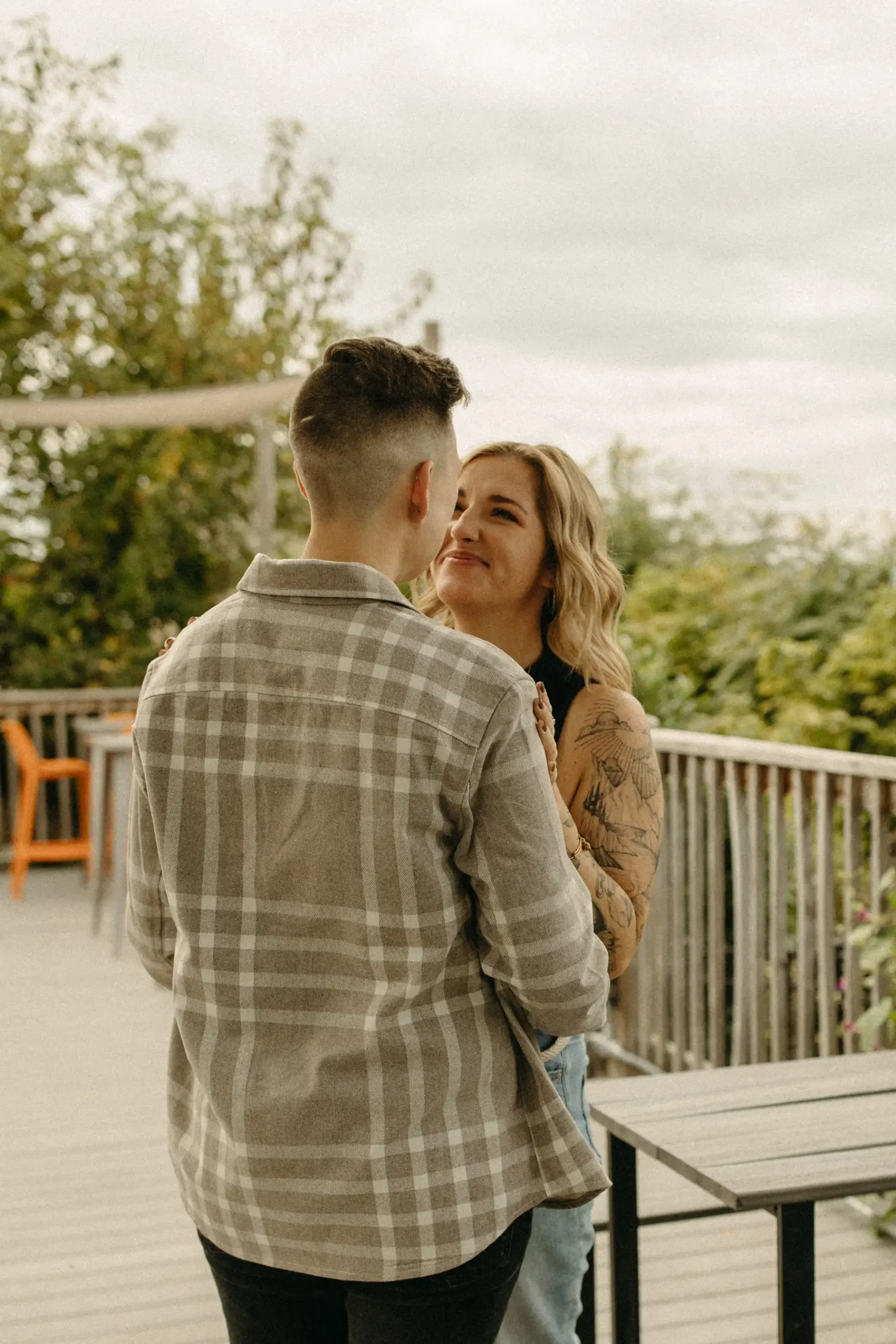 The couple shares a close moment on the deck at Gravely Brewing Co in Denver, Colorado during their engagement session.