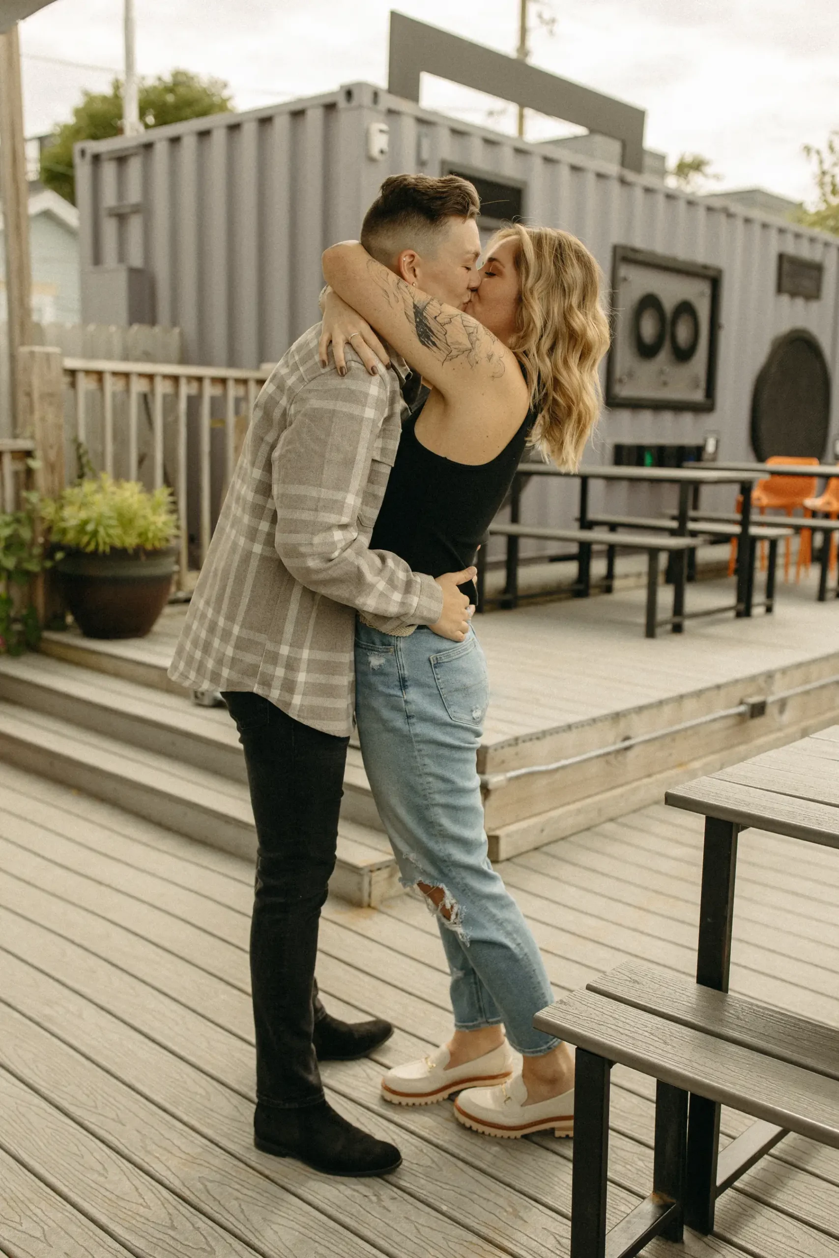 The couple shares a kiss on the outdoor deck at Gravely Brewing Co in Denver, Colorado during their engagement session.