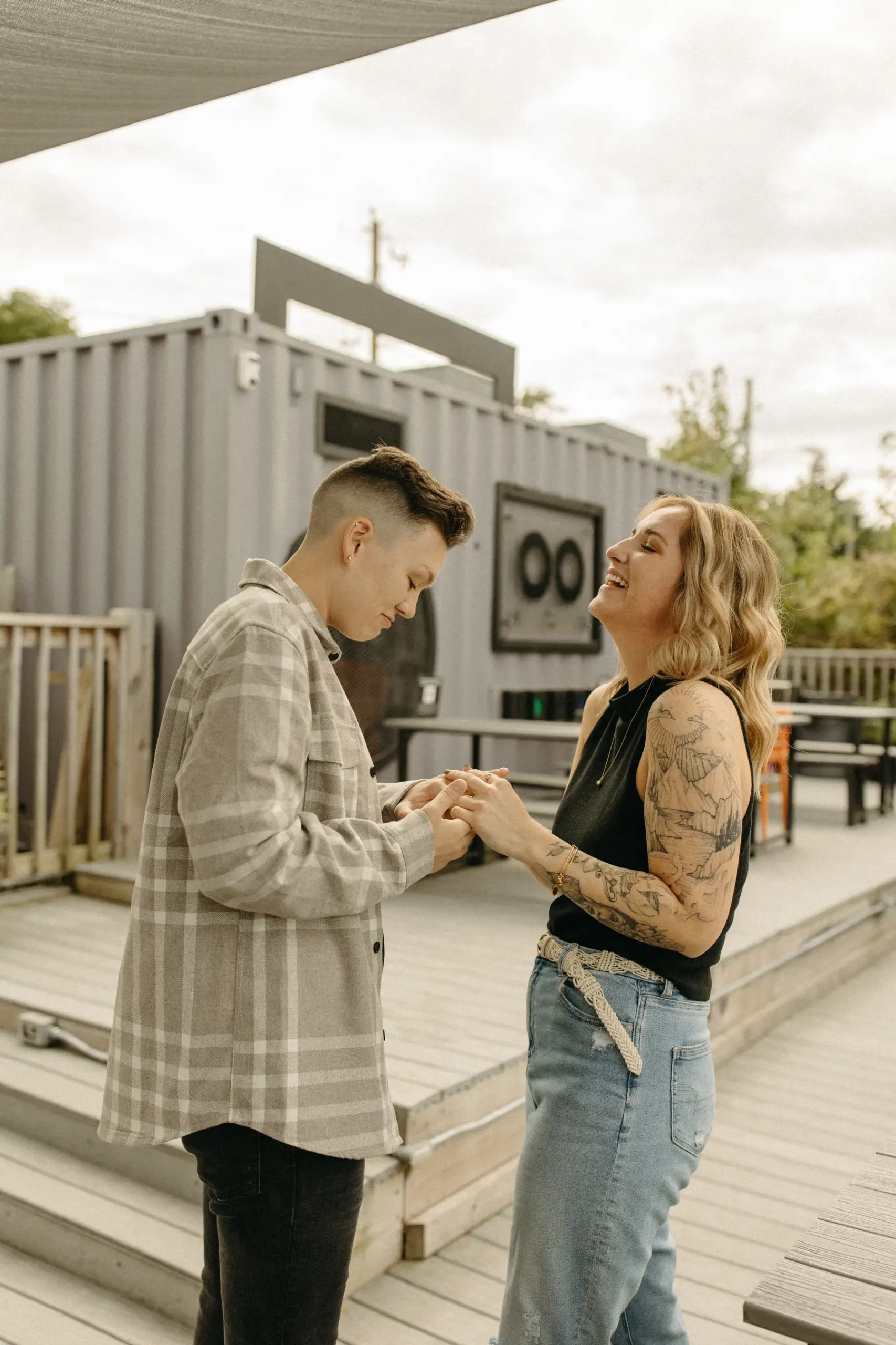 The couple holds hands and laughs together on a wooden deck outside Gravely Brewing Co in Denver, Colorado.