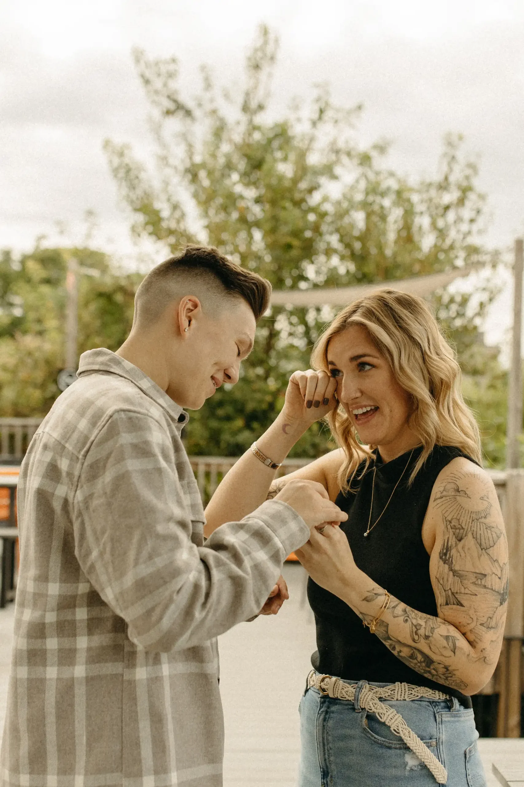 One of the partners places a ring on the other's finger as they smile and wipe away tears at Gravely Brewing Co in Denver.