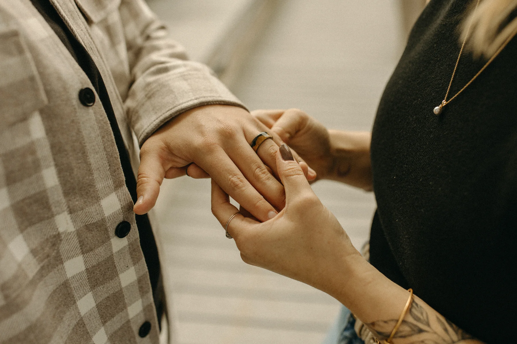 One of the partners slides a wedding band onto the other's finger during an engagement session at Gravely Brewing Co in Denver.