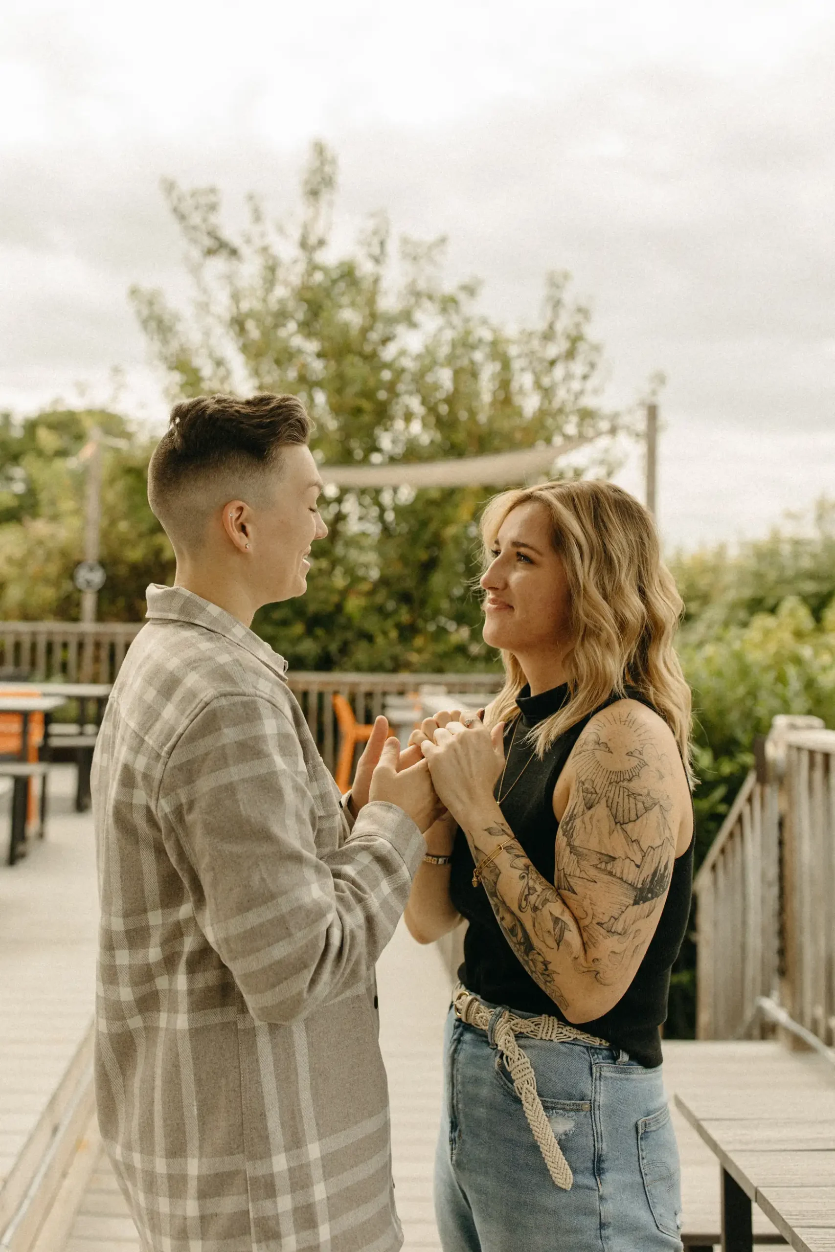 The couple holds hands and smiles at each other on the outdoor deck at Gravely Brewing Co in Denver, Colorado.