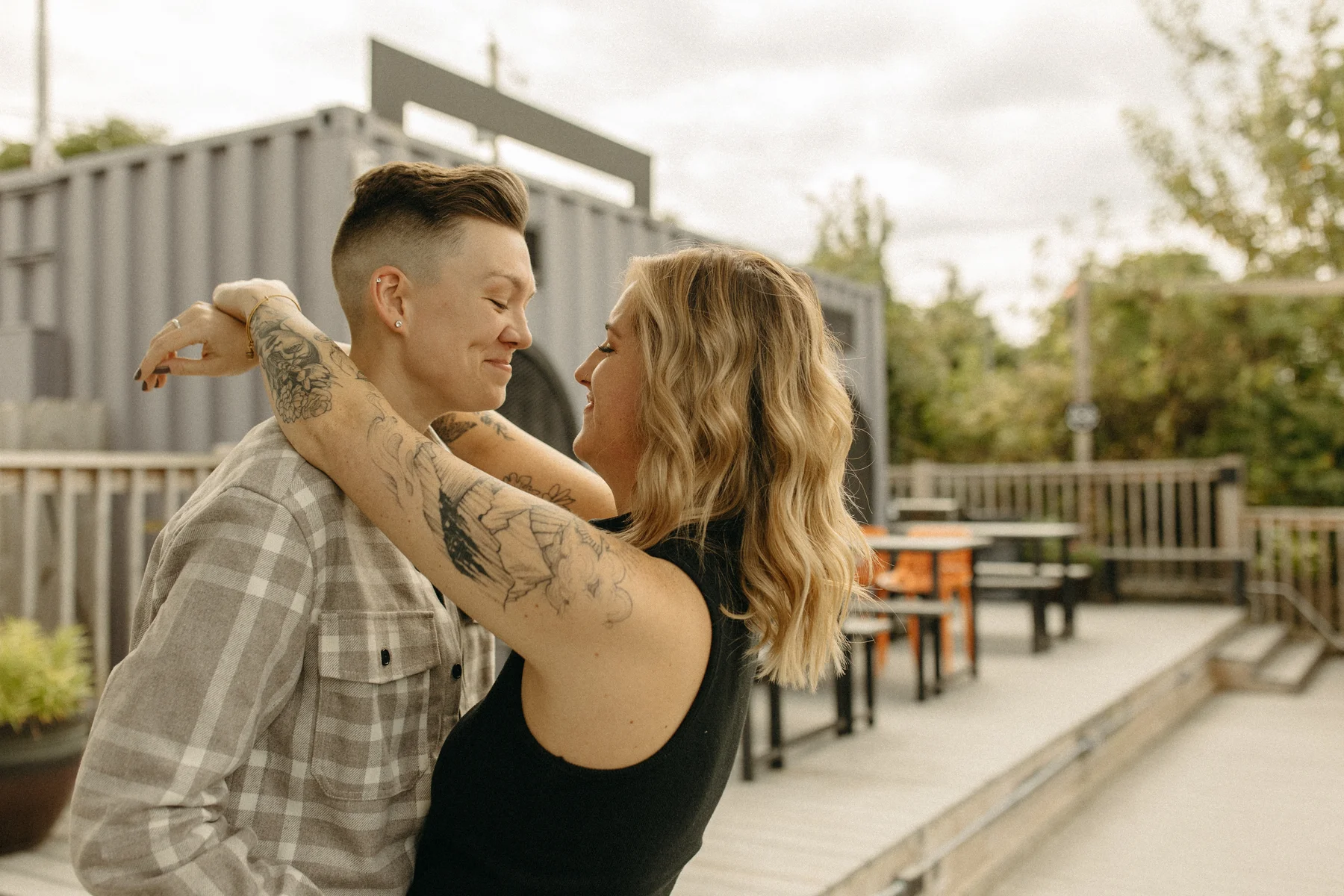 The couple embraces and smiles at each other on the outdoor patio at Gravely Brewing Co in Denver, Colorado.