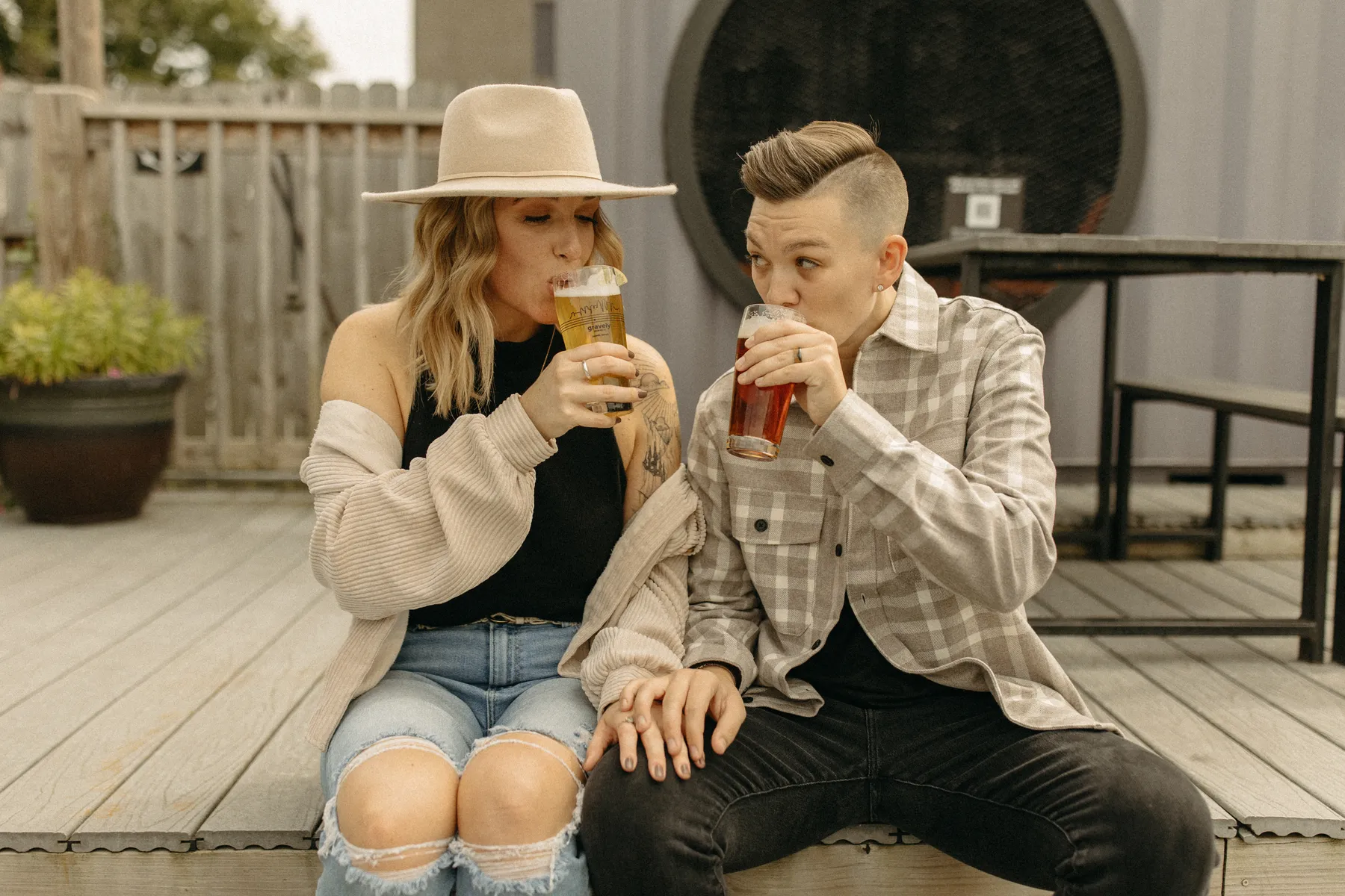 The couple sips craft beer pints while sitting on a wooden deck at Gravely Brewing Co in Denver, Colorado.