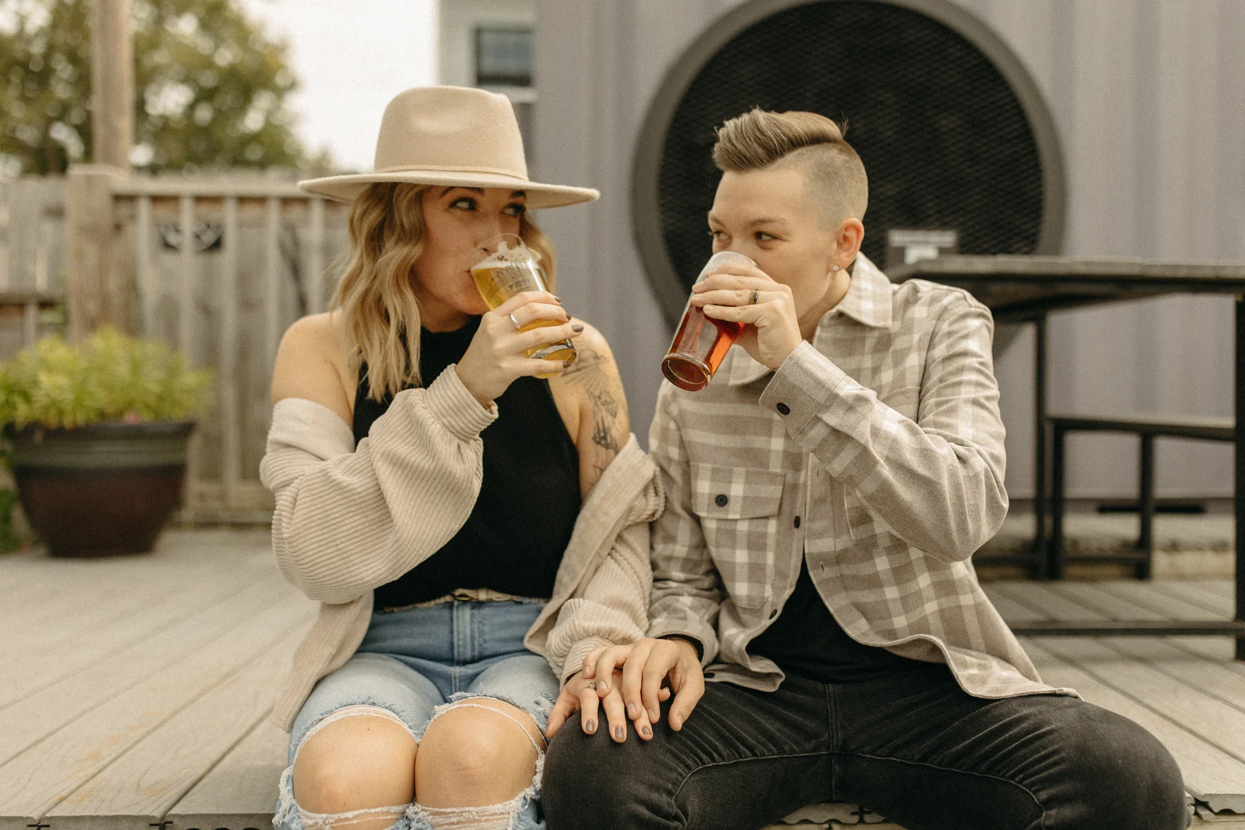 A couple sips drinks together on a deck at Gravely Brewing Co. in Denver, Colorado, during their engagement session.