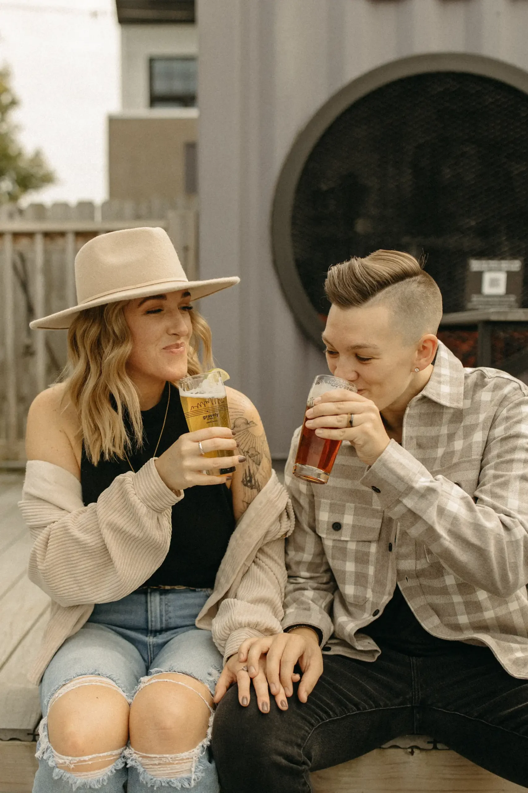 The couple sips craft beer and holds hands during their engagement session at Gravely Brewing Co. in Denver, Colorado.
