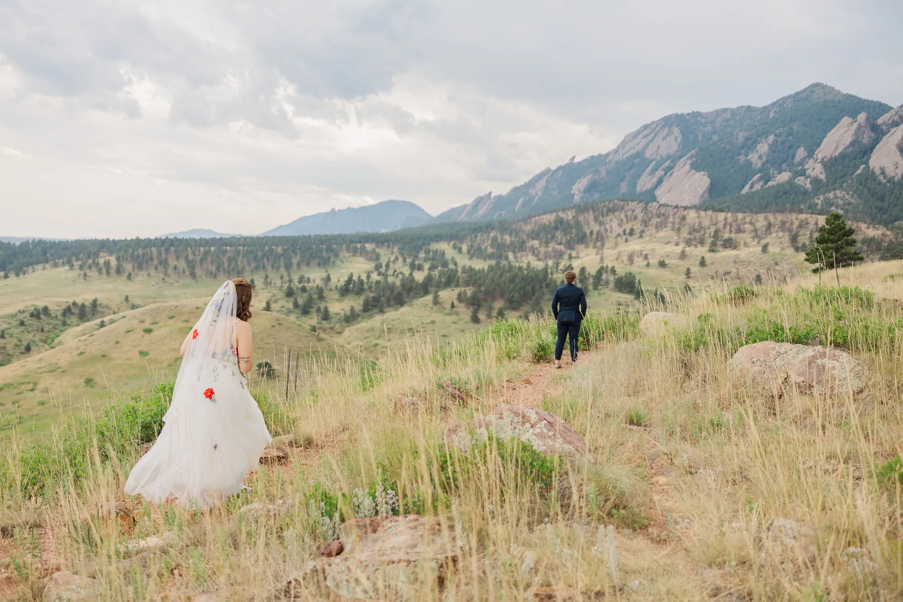 Sydney and Hannah Rusow walk a mountain trail at Halfway House in Boulder, CO, with the Flatirons in the background.