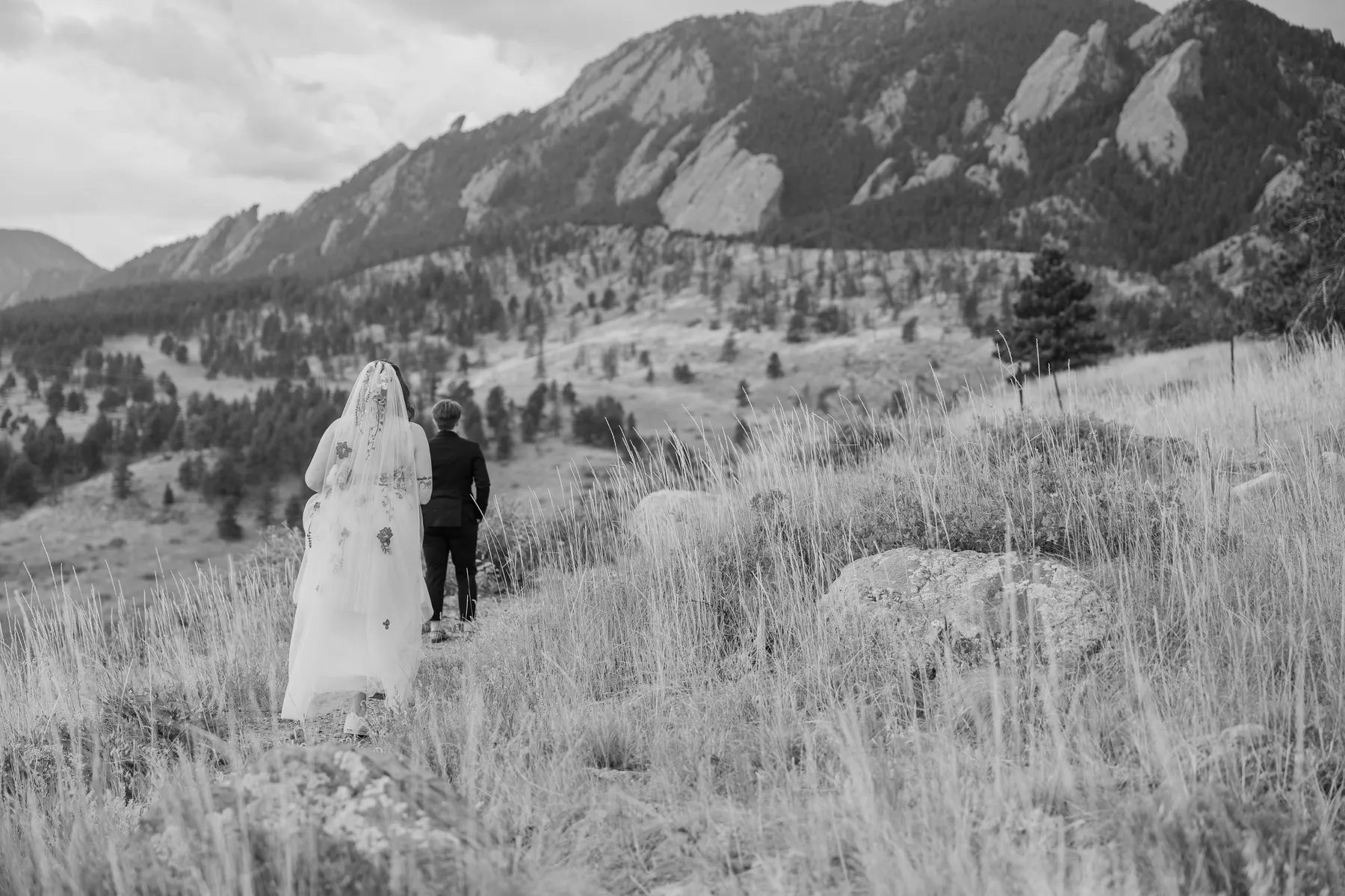 Sydney and Hannah Rusow walk hand in hand through a mountain meadow near the Flatirons at Halfway House in Boulder, CO.
