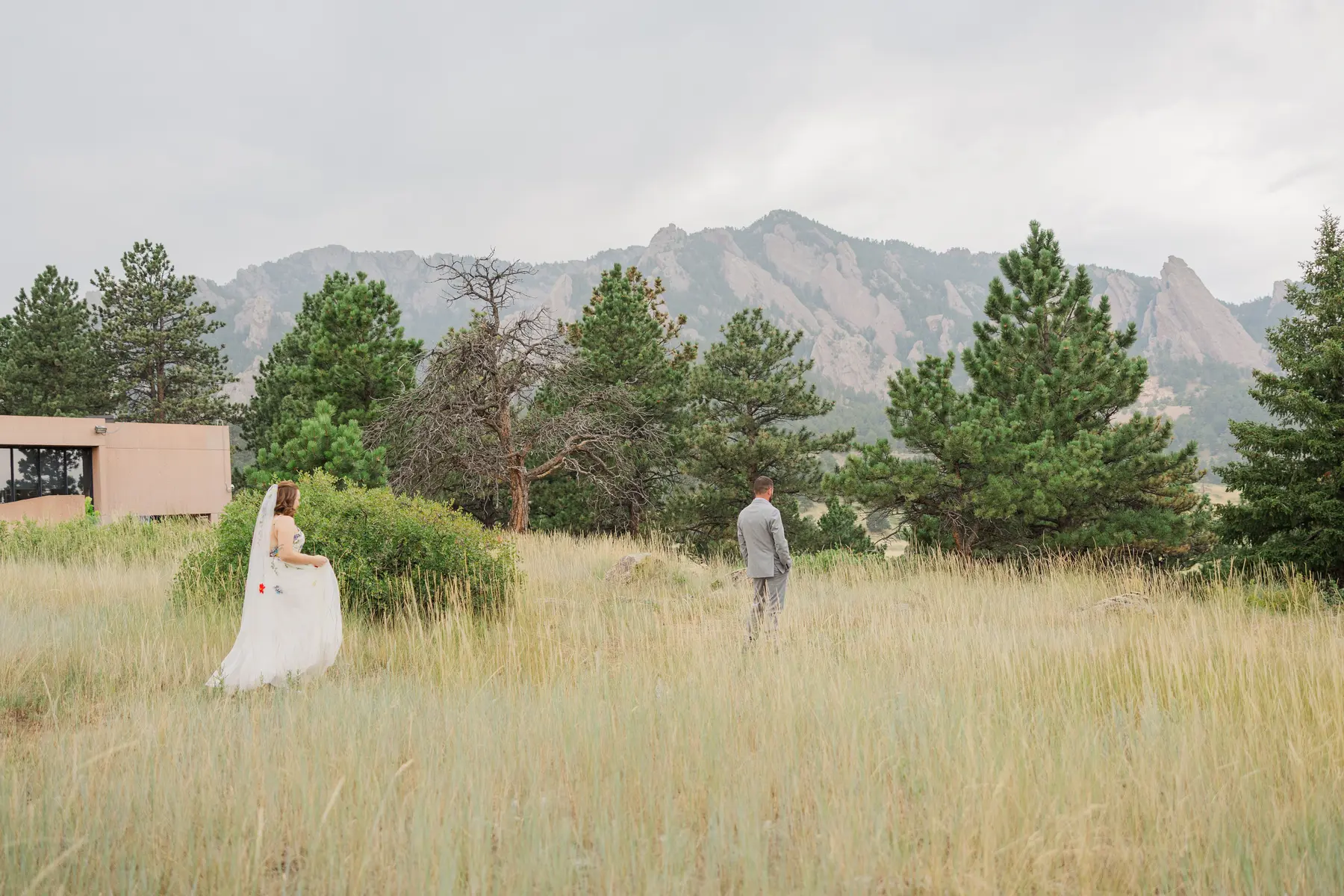 Sydney and Hannah Rusow walk through a golden meadow with the Flatirons in the background at Halfway House in Boulder, CO.