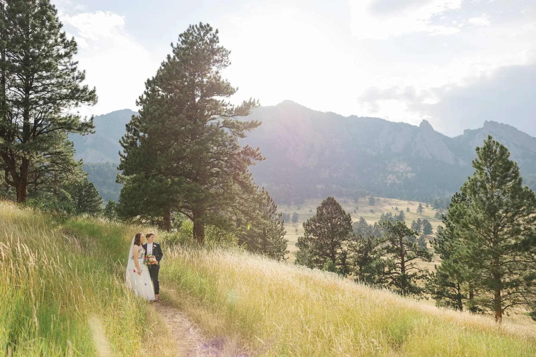 Sydney and Hannah Rusow walk through a sunlit mountain meadow at Halfway House in Boulder, CO.