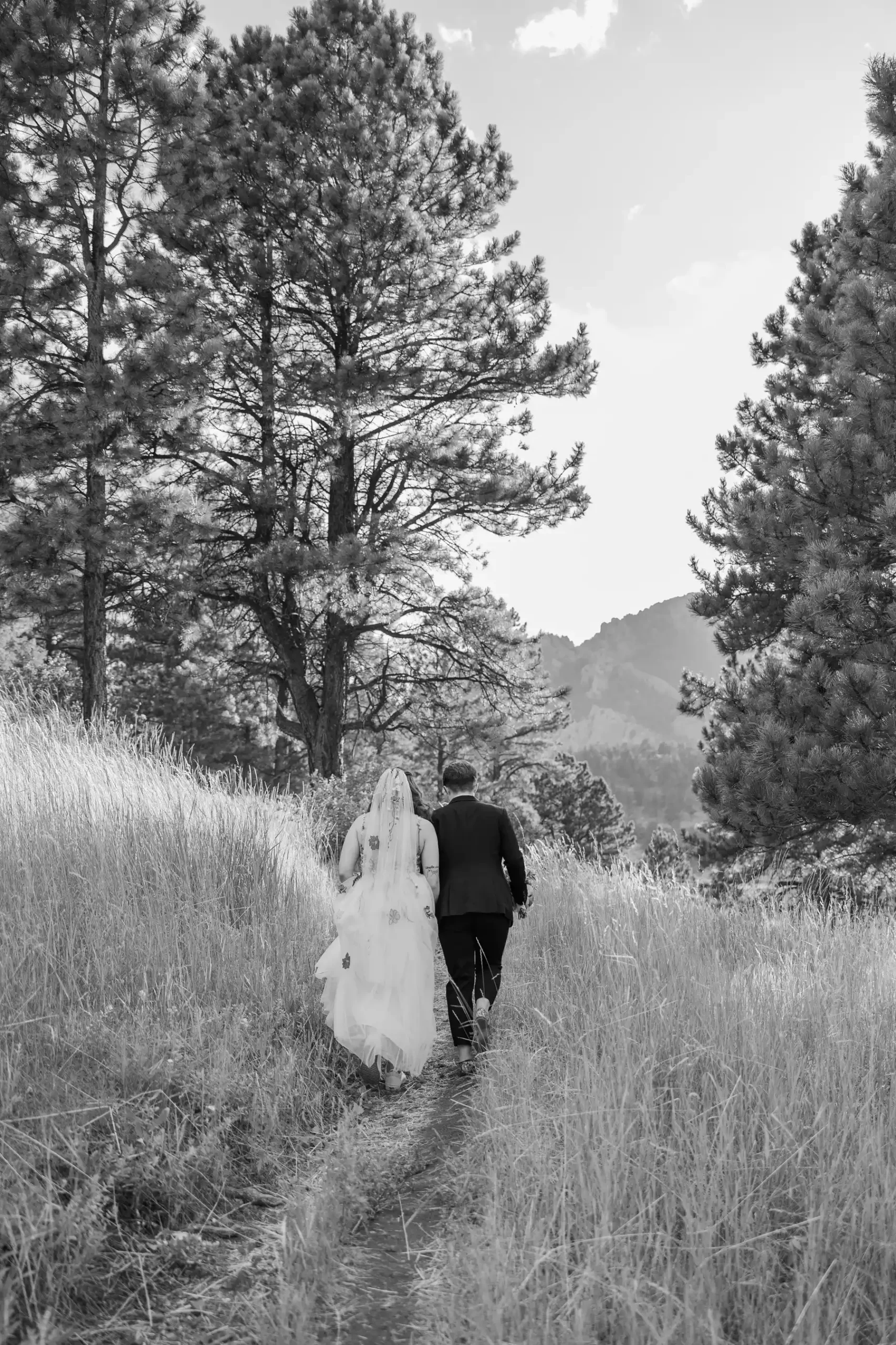 Sydney and Hannah Rusow walk hand-in-hand along a mountain trail at Halfway House in Boulder, CO.