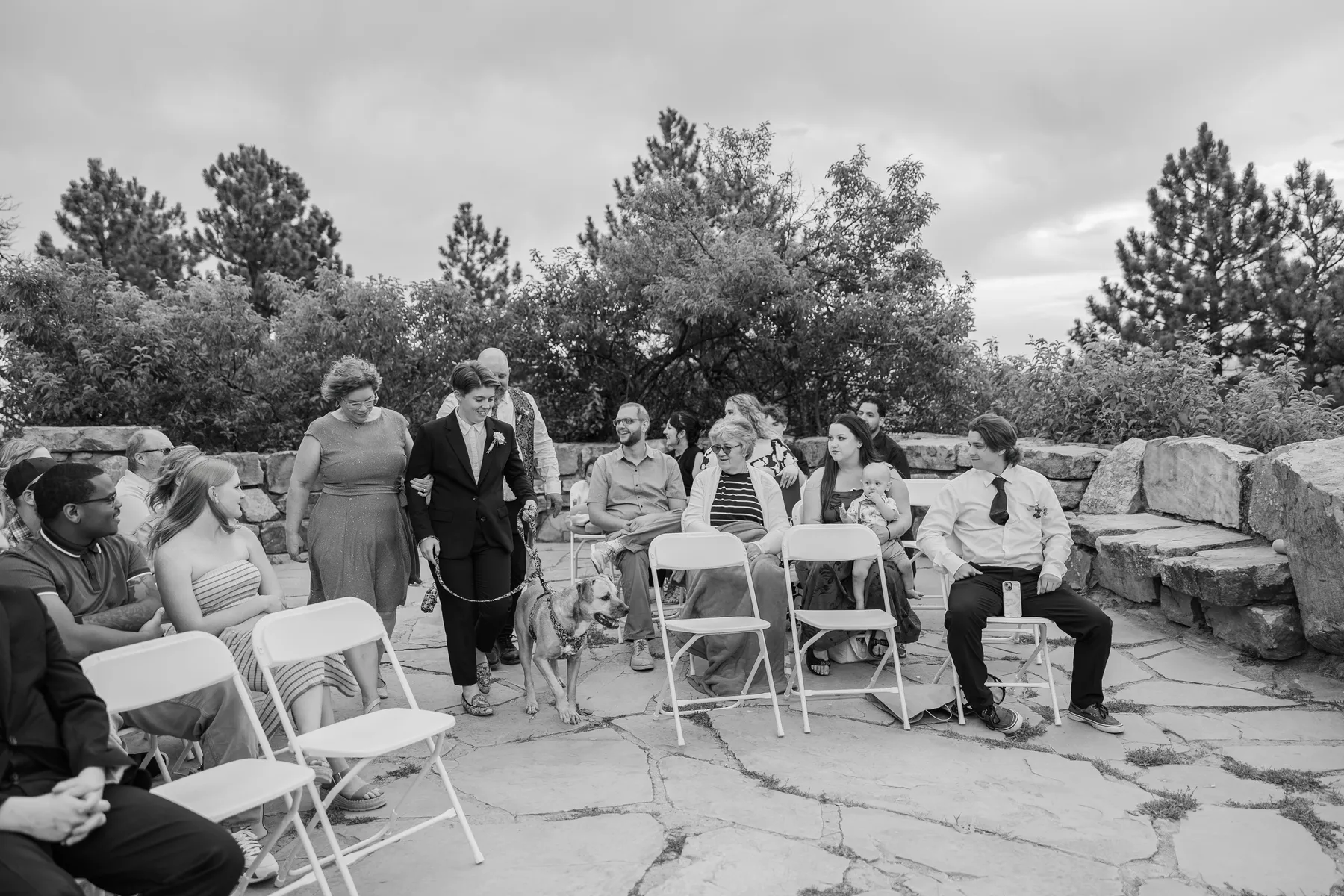 Sydney Rusow walks down the aisle with a dog and escort at Halfway House in Boulder, CO.