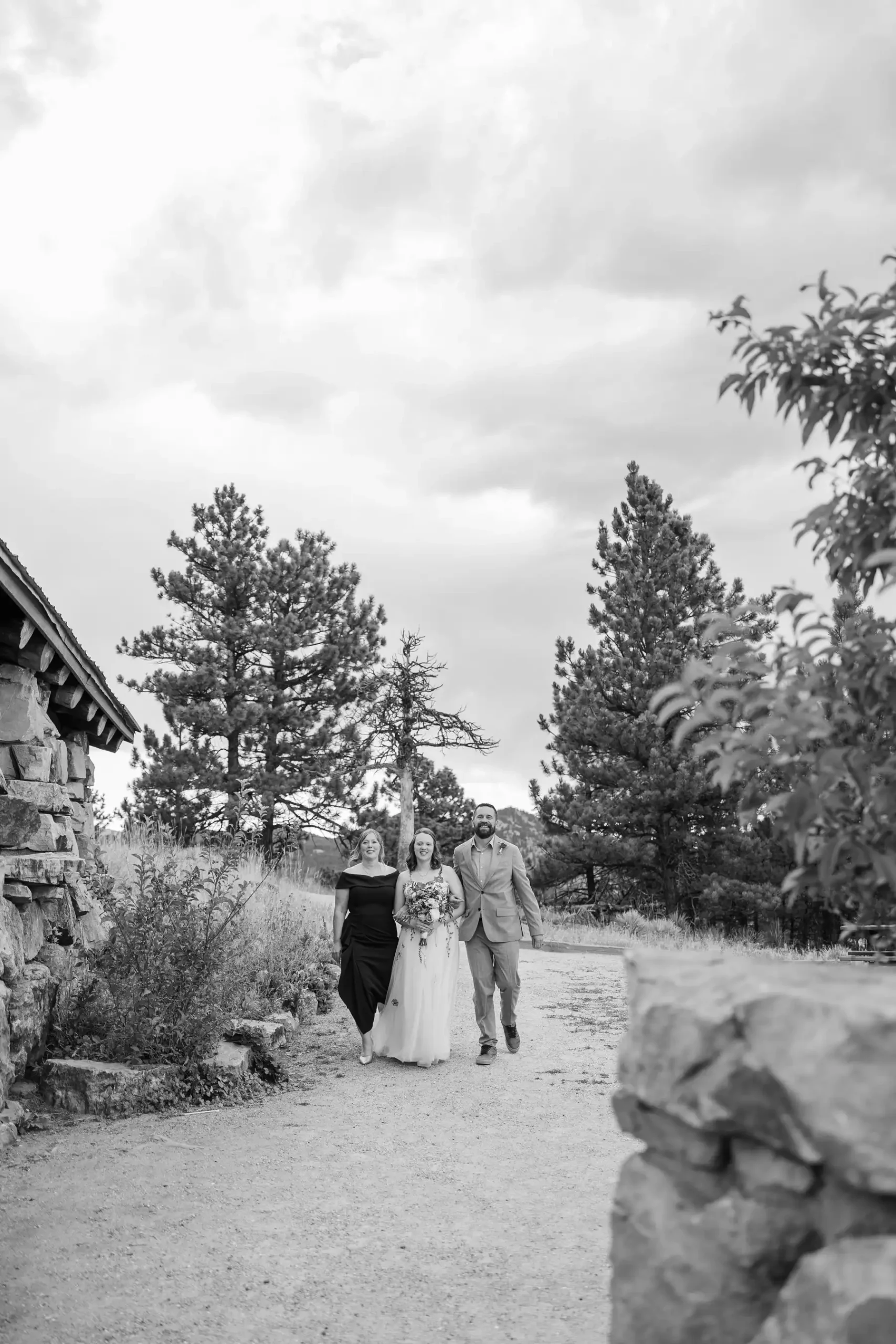 Hannah Rusow walks down a gravel path flanked by two loved ones at Halfway House in Boulder, CO.