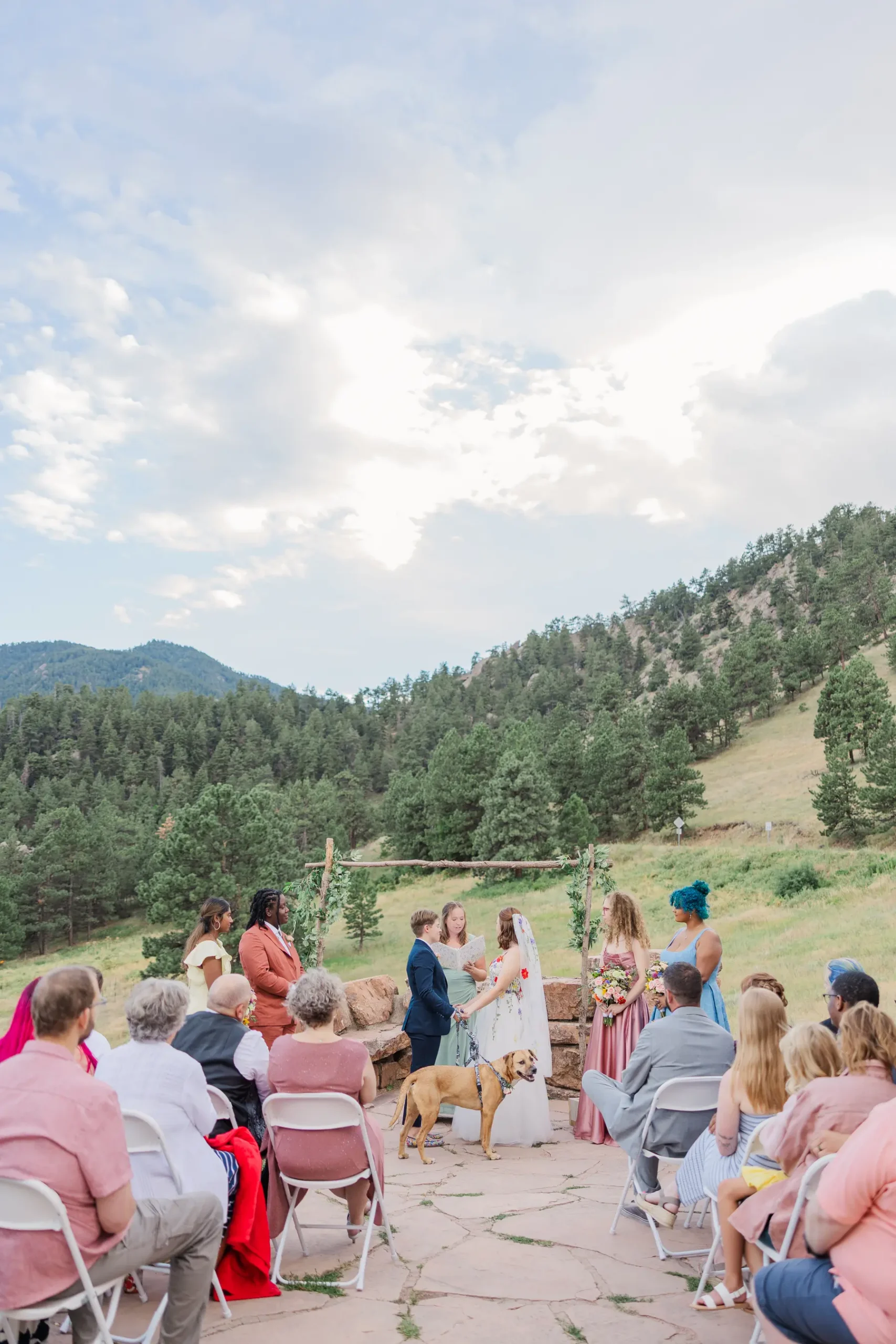 Sydney and Hannah Rusow exchange vows at an outdoor ceremony at Halfway House in Boulder, CO, with mountain views.