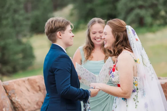 Sydney and Hannah Rusow laugh together during their outdoor wedding ceremony at Halfway House in Boulder, CO.