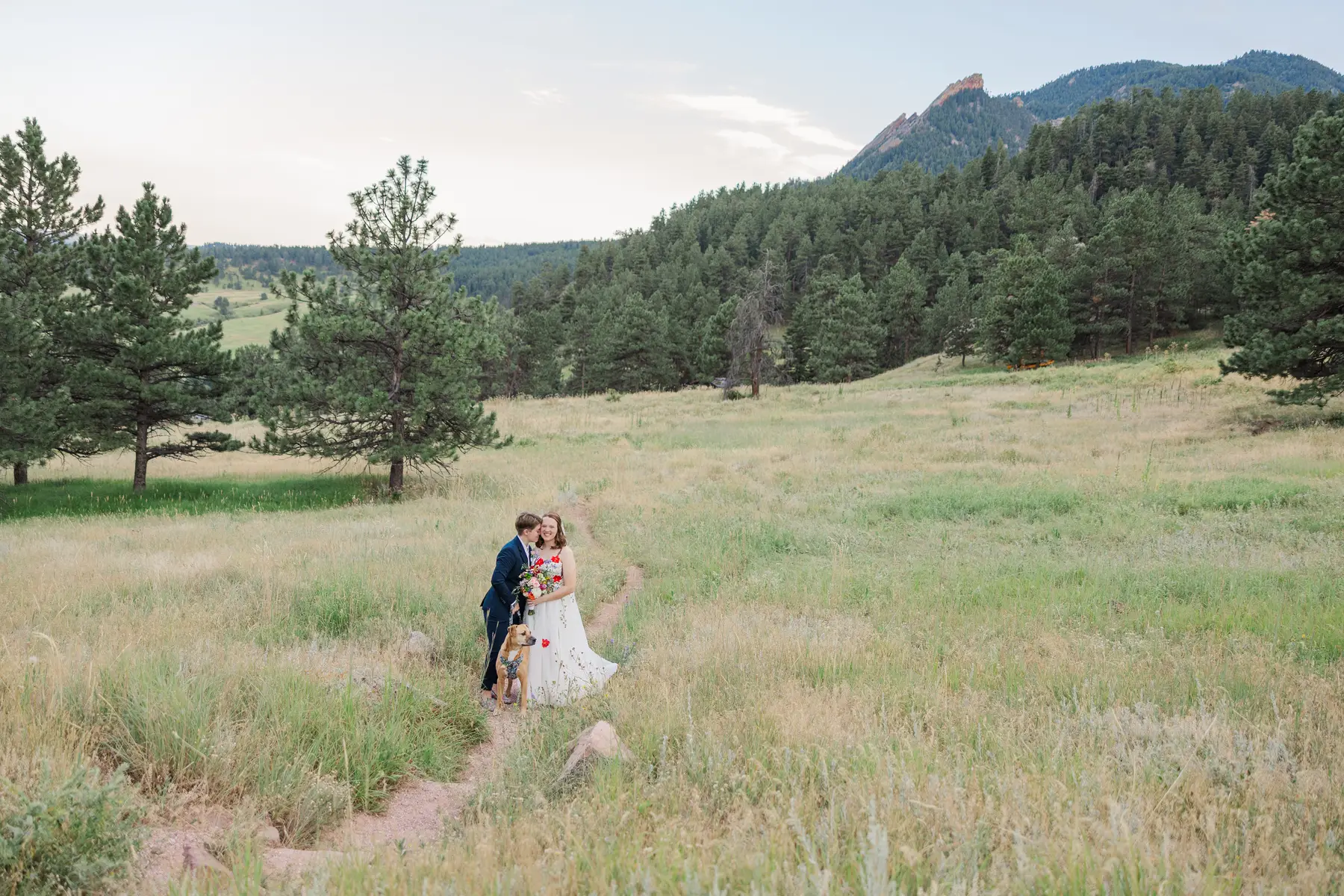 Sydney and Hannah Rusow share a joyful moment on a meadow trail with their dog at Chautauqua Park near Boulder, CO.