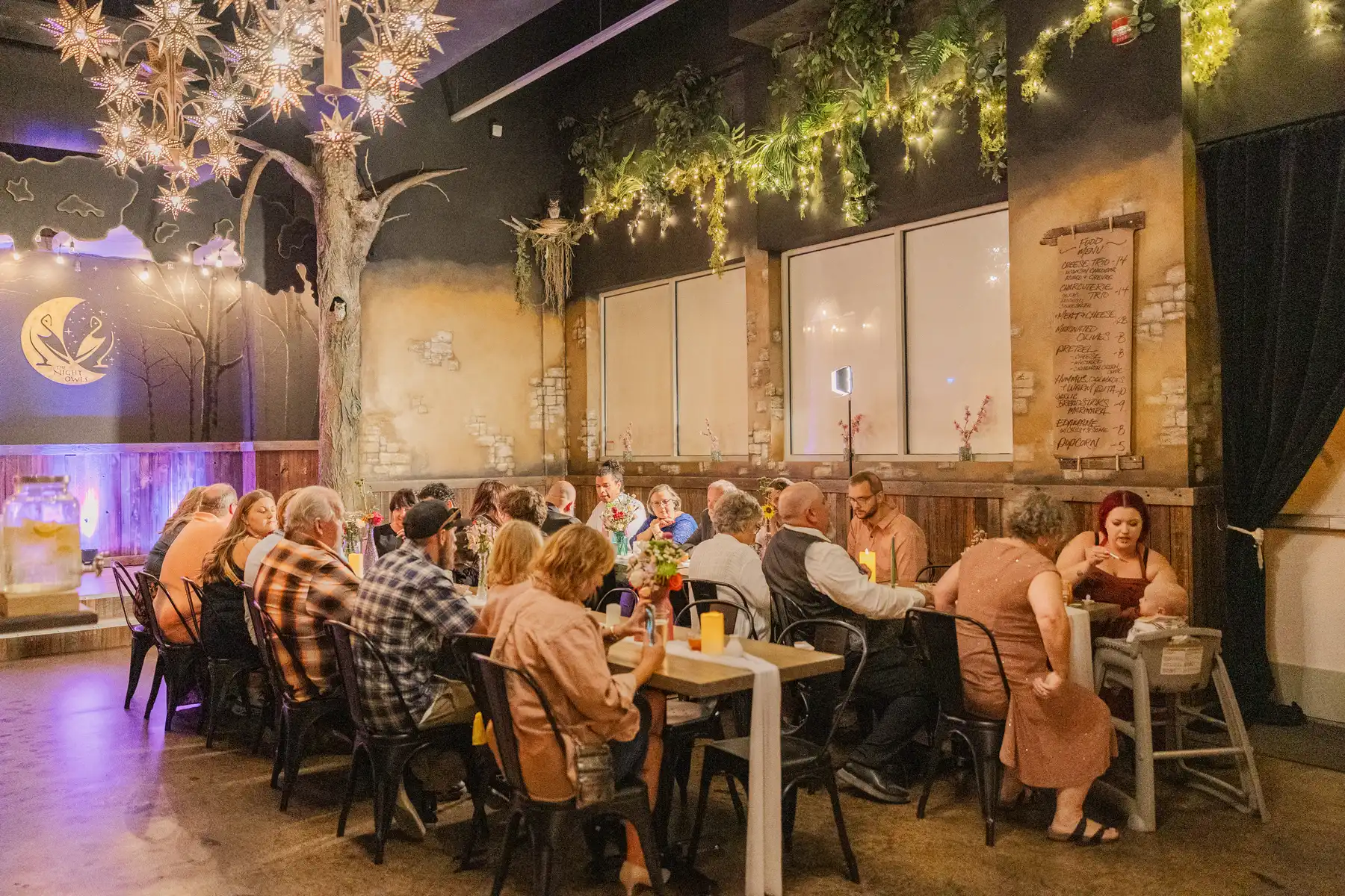 Guests dine at long tables inside the Night Owl at Halfway House in Boulder, CO, at Sydney and Hannah Rusow's wedding reception.