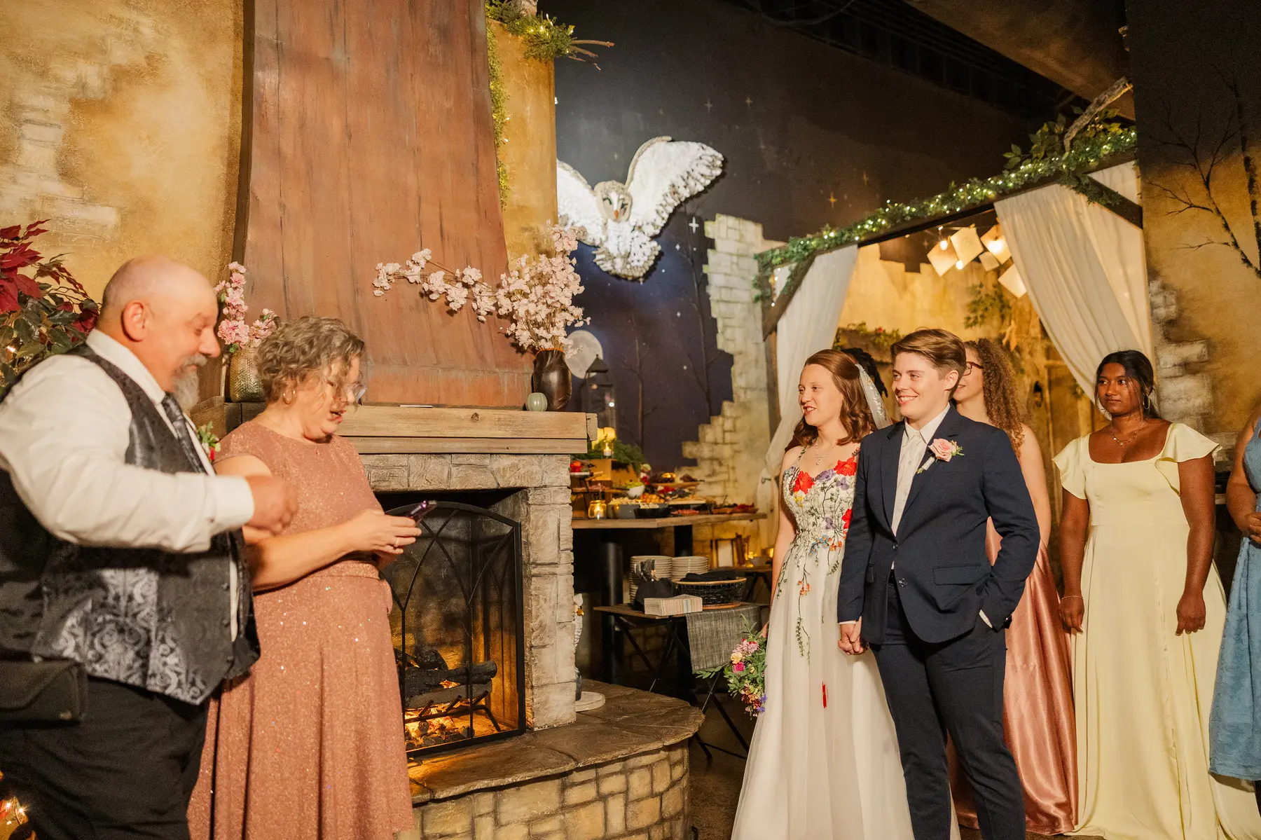 Sydney and Hannah Rusow smile as guests give a toast by a stone fireplace at Halfway House in Boulder, CO.