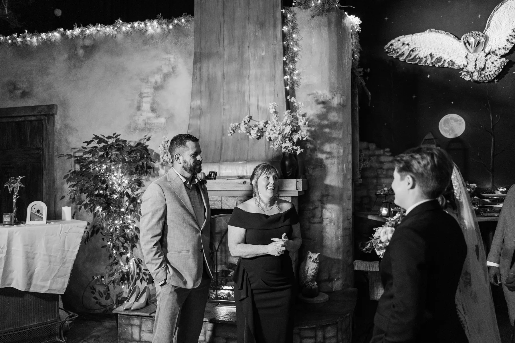 Guests mingle with a wedding guest in a black dress at Halfway House in Boulder, CO, decorated with owl decor and string lights.