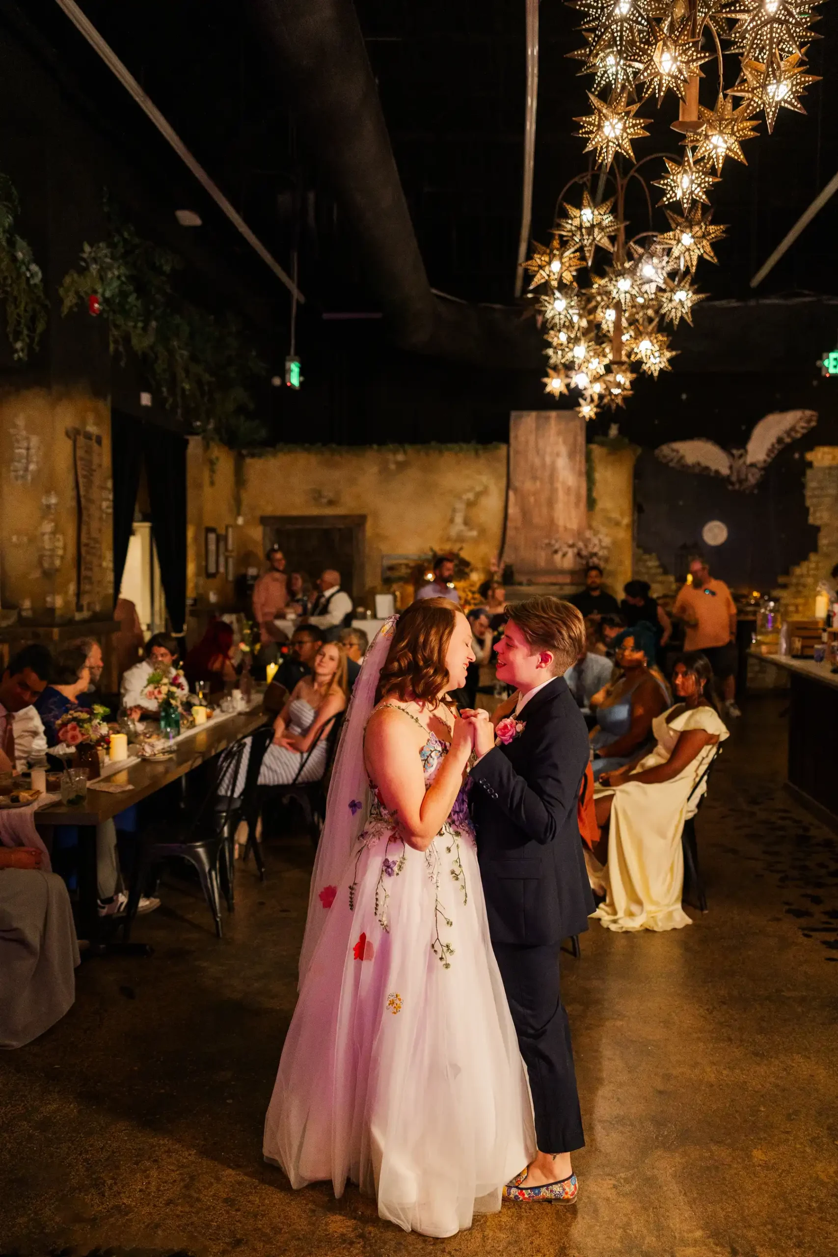 Sydney and Hannah Rusow share their first dance under star-shaped chandeliers at Halfway House in Boulder, CO.