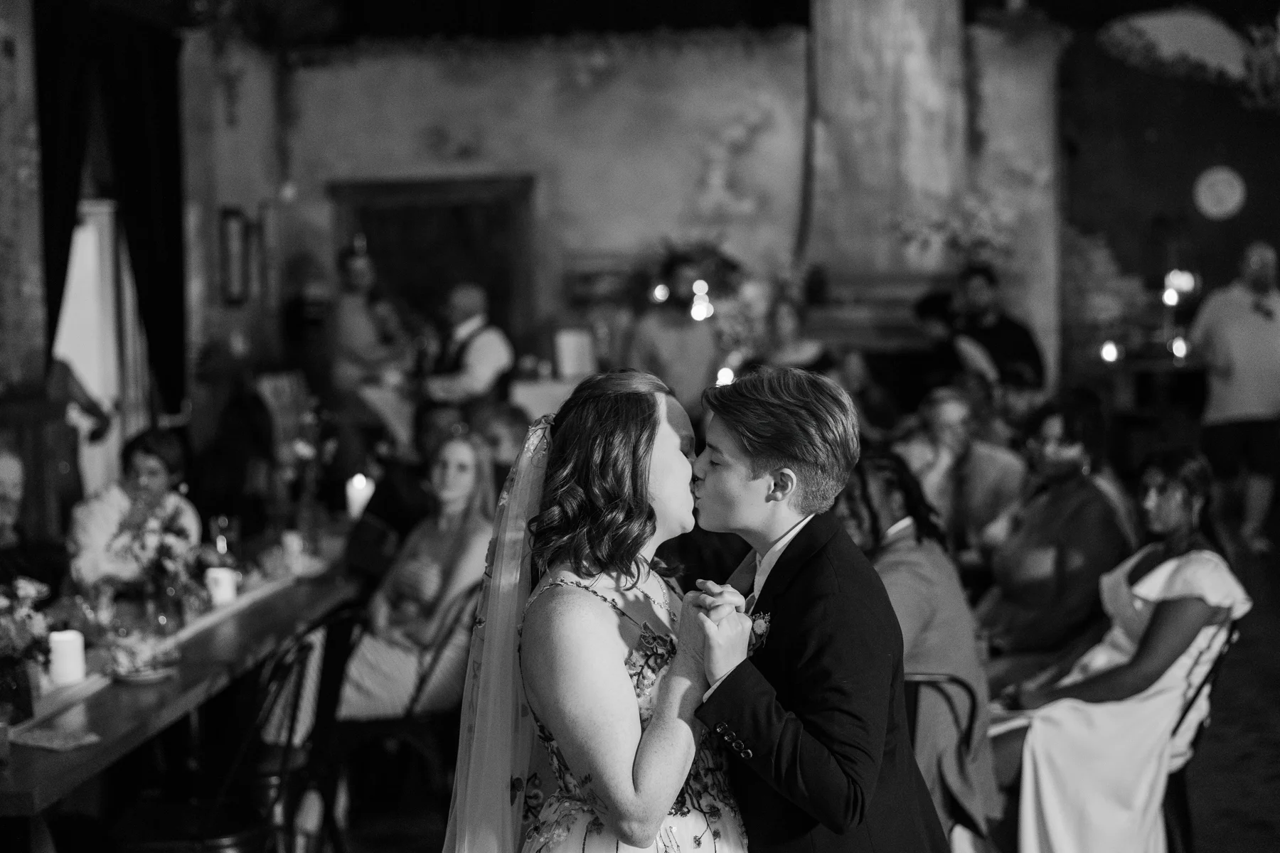 Sydney and Hannah Rusow share a first dance kiss at Halfway House in Boulder, CO, surrounded by wedding guests.