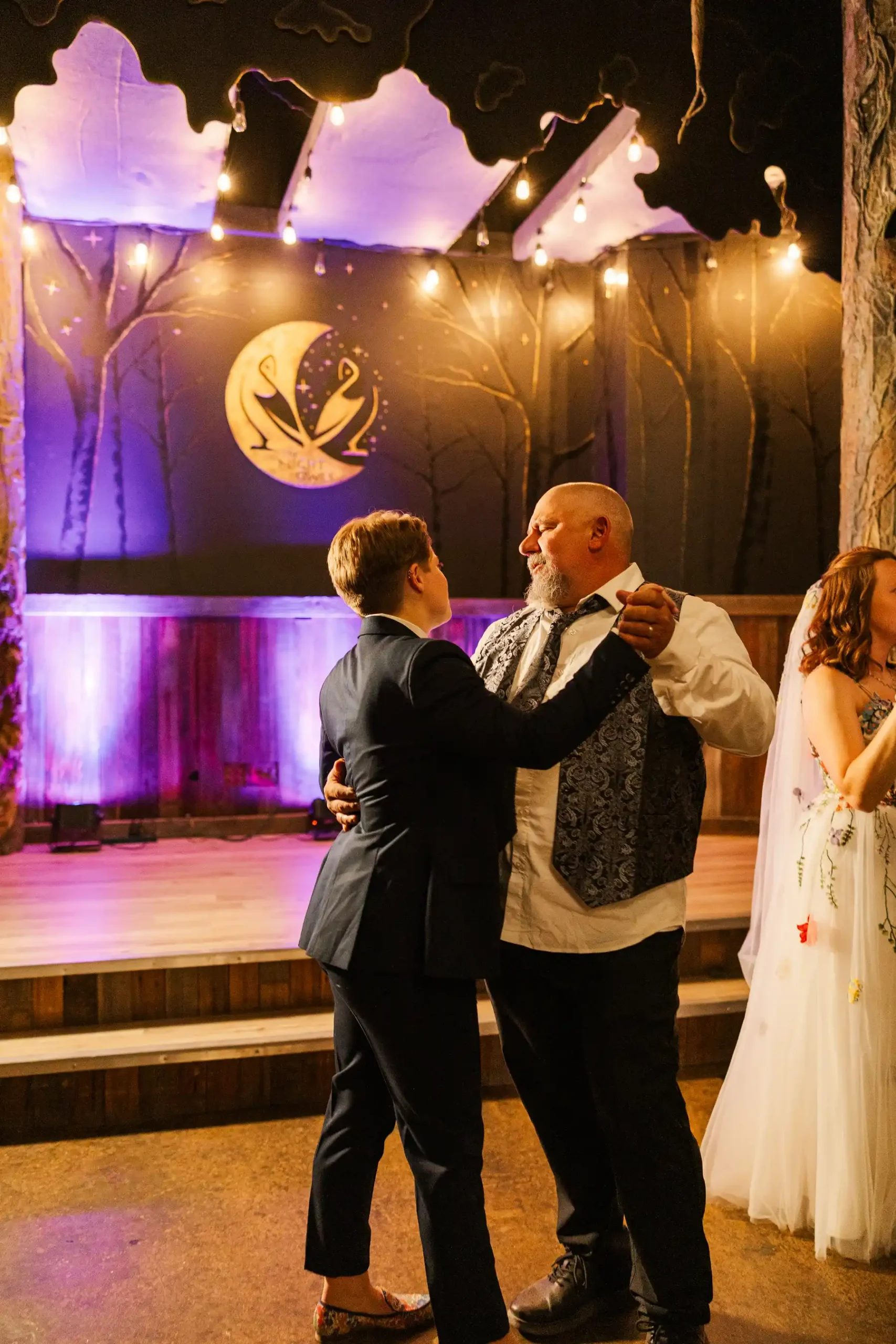 A guest dances with a person in a patterned vest at Sydney and Hannah Rusow's wedding reception at Halfway House in Boulder, CO.