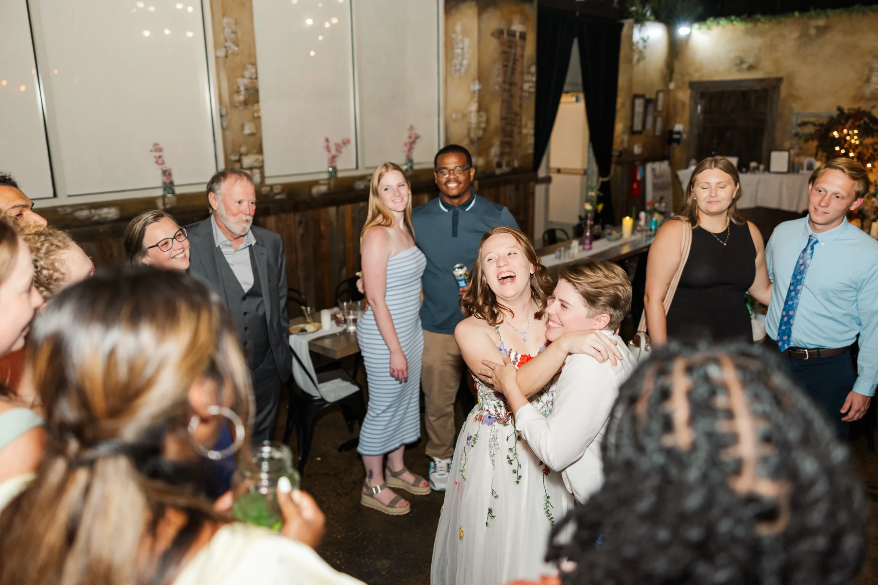 Guests laugh and embrace on the dance floor at Sydney and Hannah Rusow's wedding reception at Halfway House in Boulder, CO.
