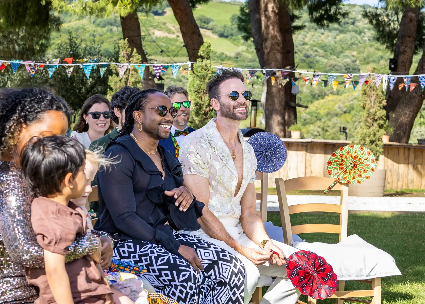 Two grooms laugh with guests during an outdoor ceremony at Conti di San Bonifacio Wine Resort in Tuscany, Italy.