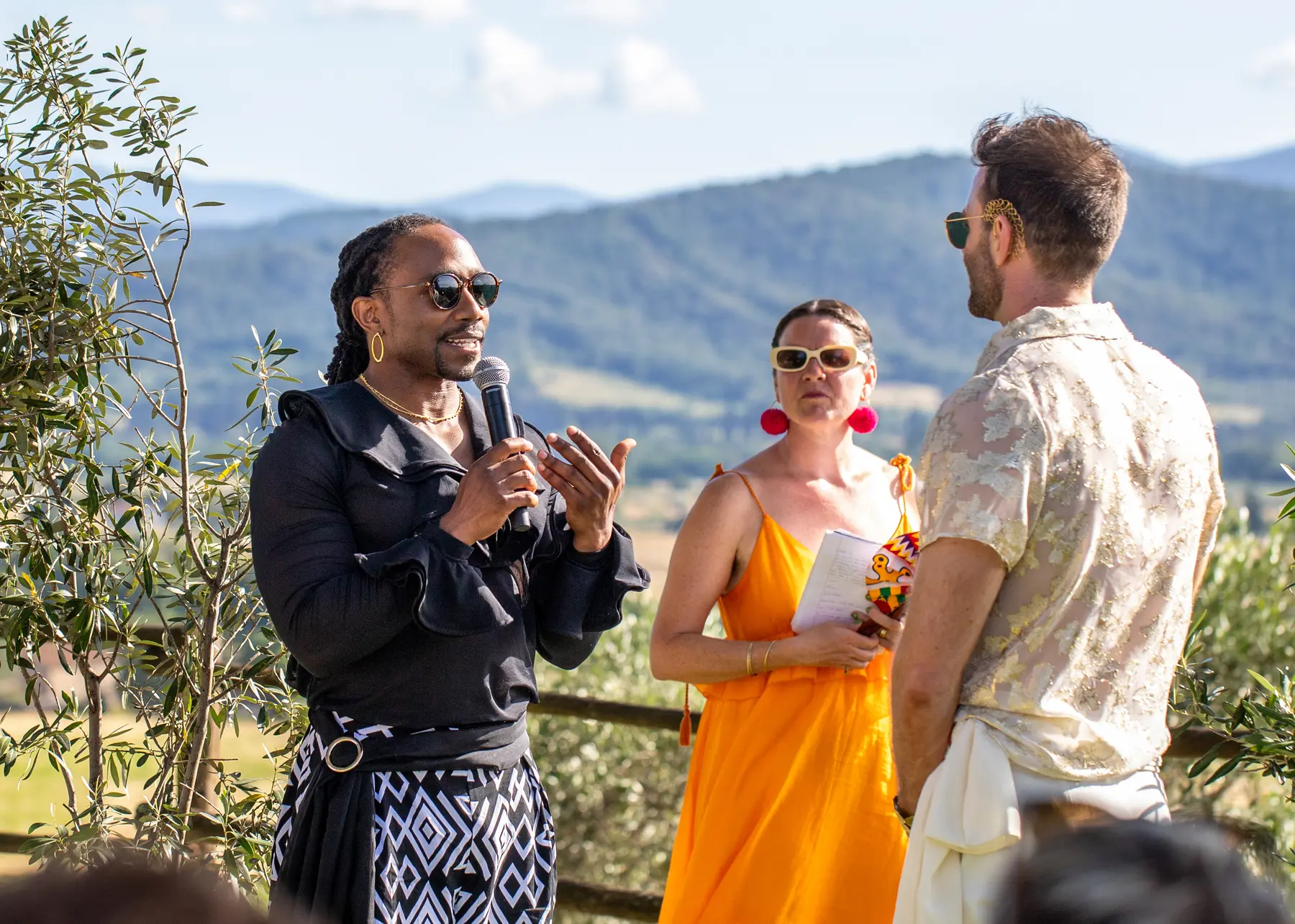 A groom speaks into a microphone during an outdoor ceremony at Conti di San Bonifacio Wine Resort in Tuscany, Italy.