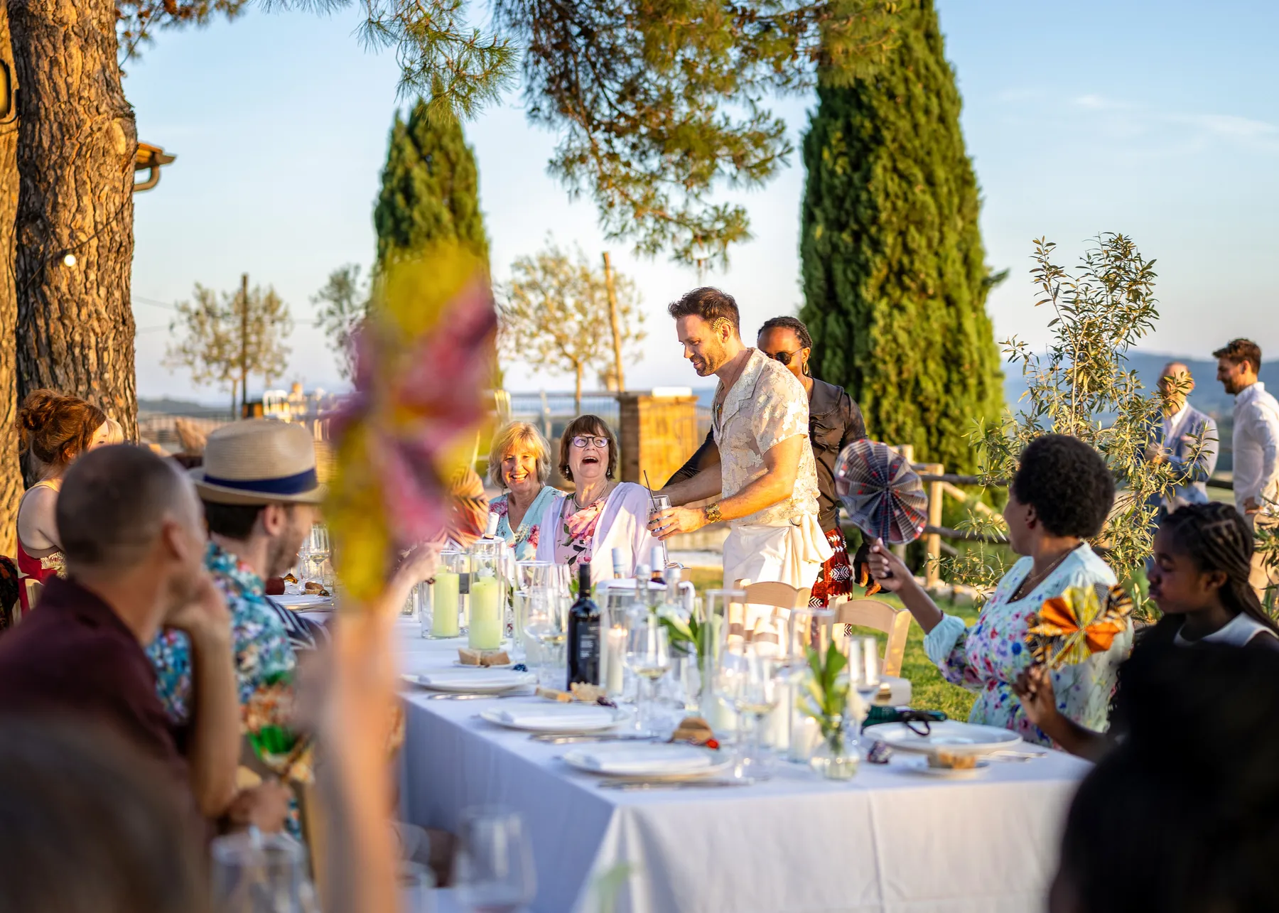 Guests laugh and celebrate at an outdoor reception dinner at Conti di San Bonifacio Wine Resort in Tuscany, Italy.