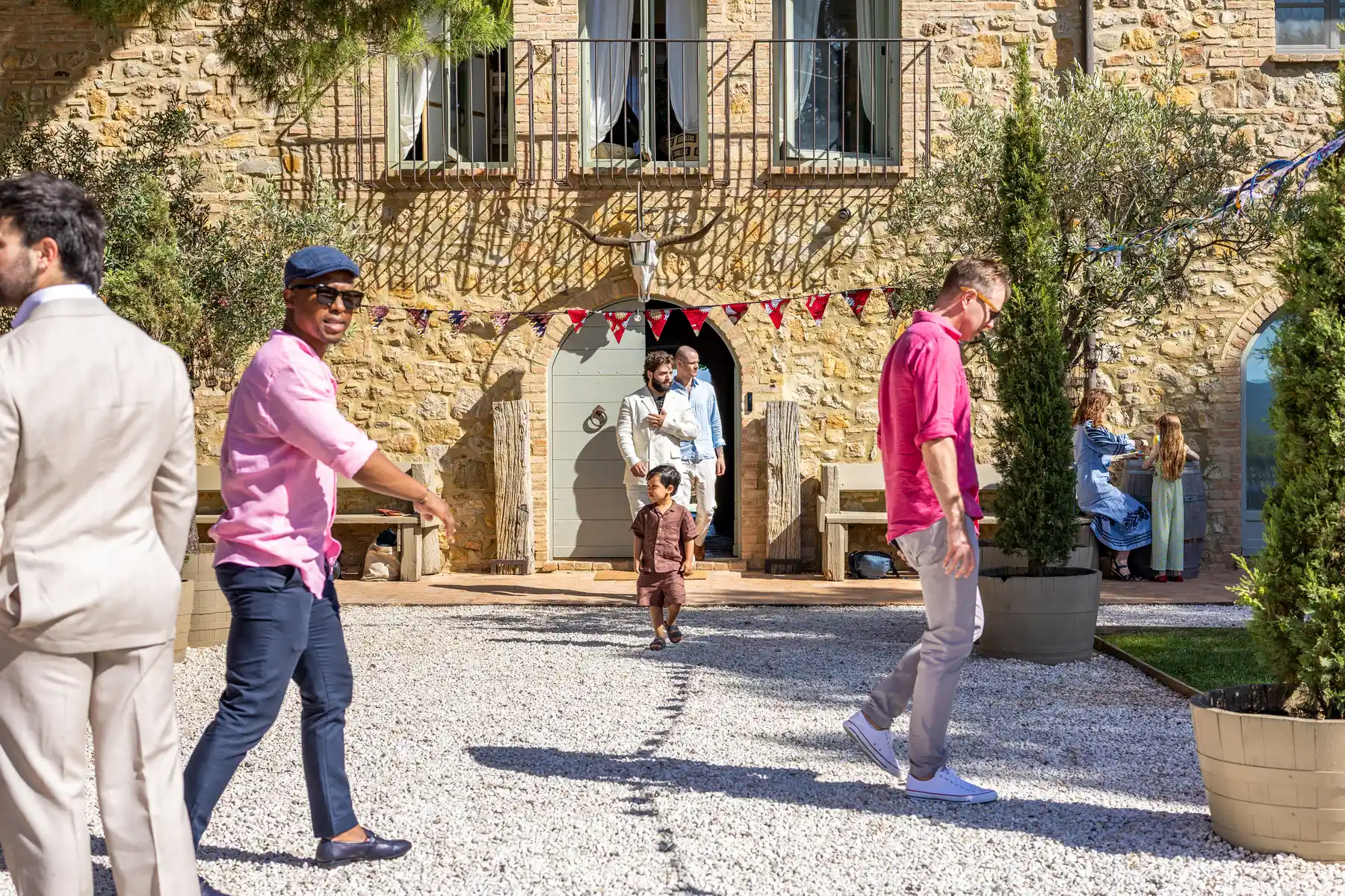 Guests mingle in the sunny gravel courtyard outside Conti di San Bonifacio Wine Resort in Tuscany, Italy.