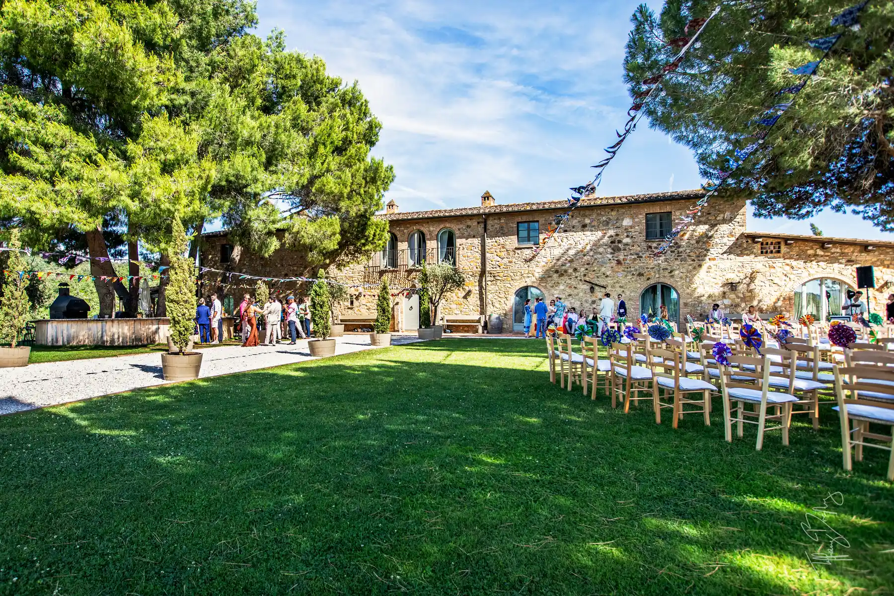 Outdoor wedding ceremony setup with wooden chairs and colorful decorations at Conti di San Bonifacio Wine Resort in Tuscany.