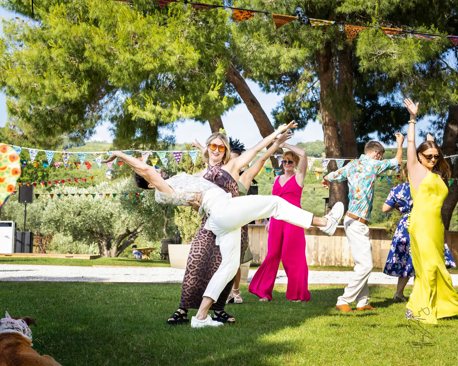 Guests dance and dip on the lawn at Conti di San Bonifacio Wine Resort in Tuscany, Italy, during a vibrant outdoor wedding reception.