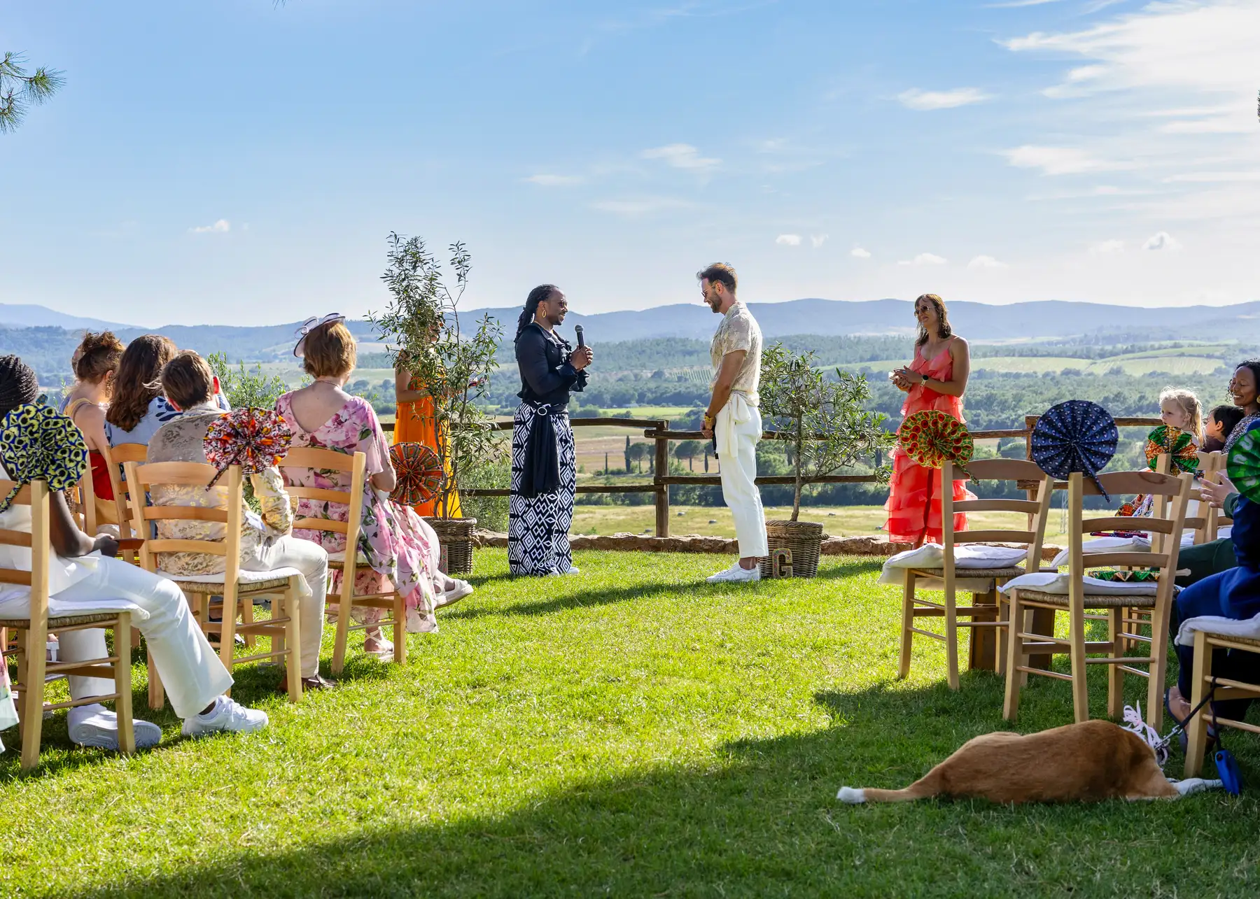 Two grooms stand with their officiant during an outdoor ceremony at Conti di San Bonifacio Wine Resort in Tuscany, Italy.