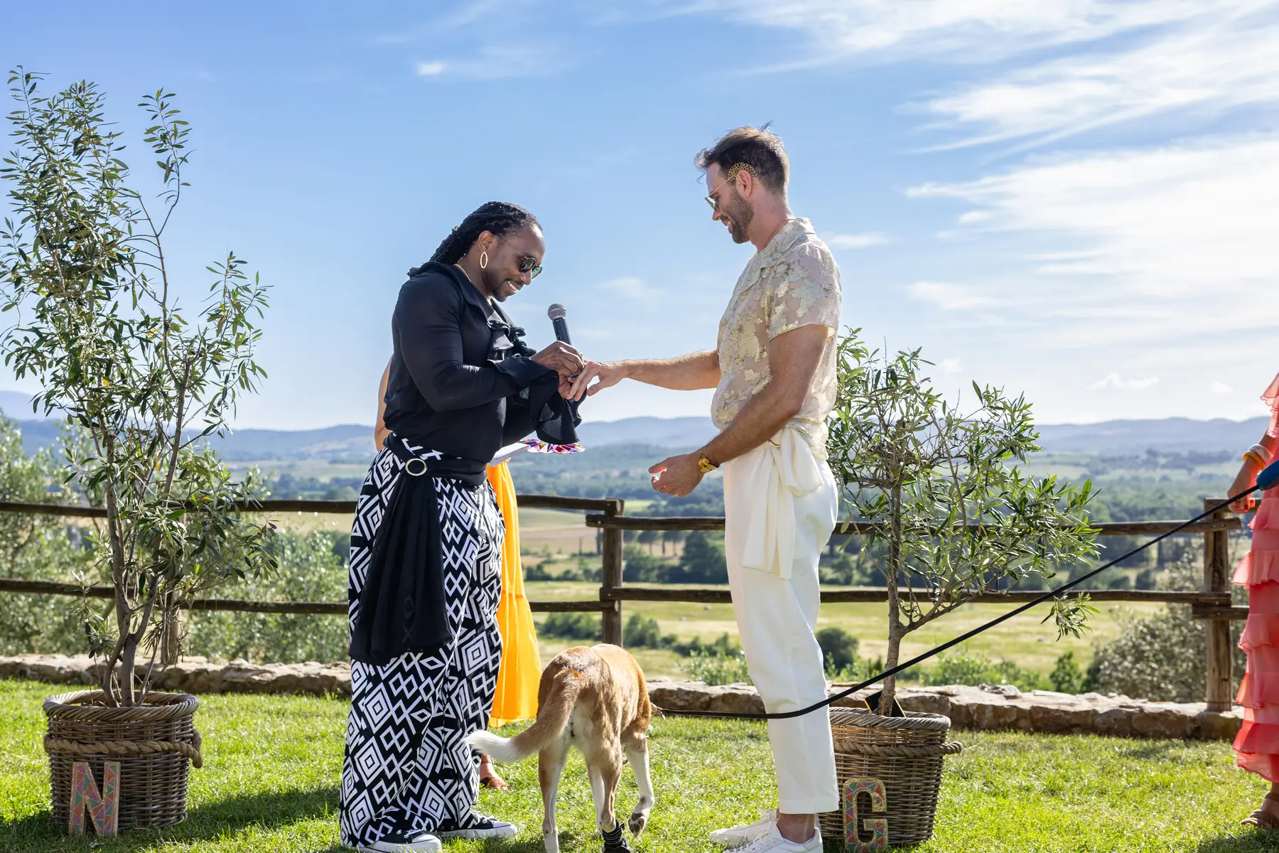 A groom places a ring on his partner's finger during an outdoor ceremony at Conti di San Bonifacio Wine Resort in Tuscany.