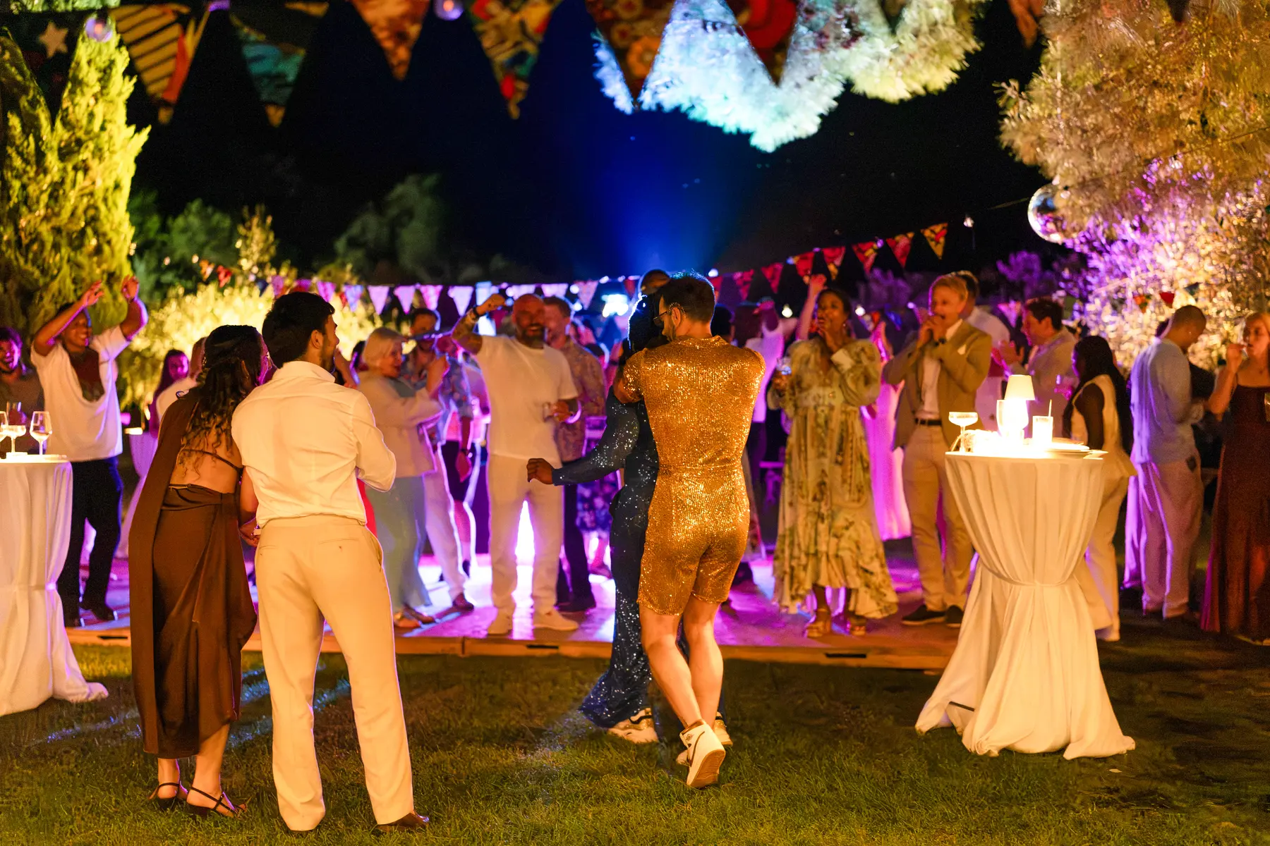 Guests and grooms dance under colorful bunting at an outdoor evening reception at Conti di San Bonifacio Wine Resort in Tuscany.