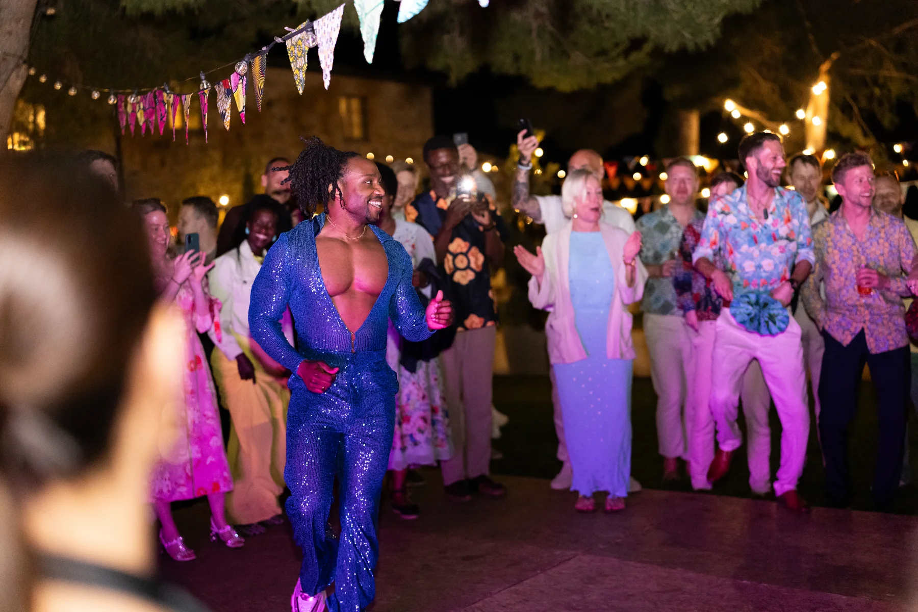 A performer in a blue sequined jumpsuit dances at an outdoor evening reception at Conti di San Bonifacio in Tuscany.