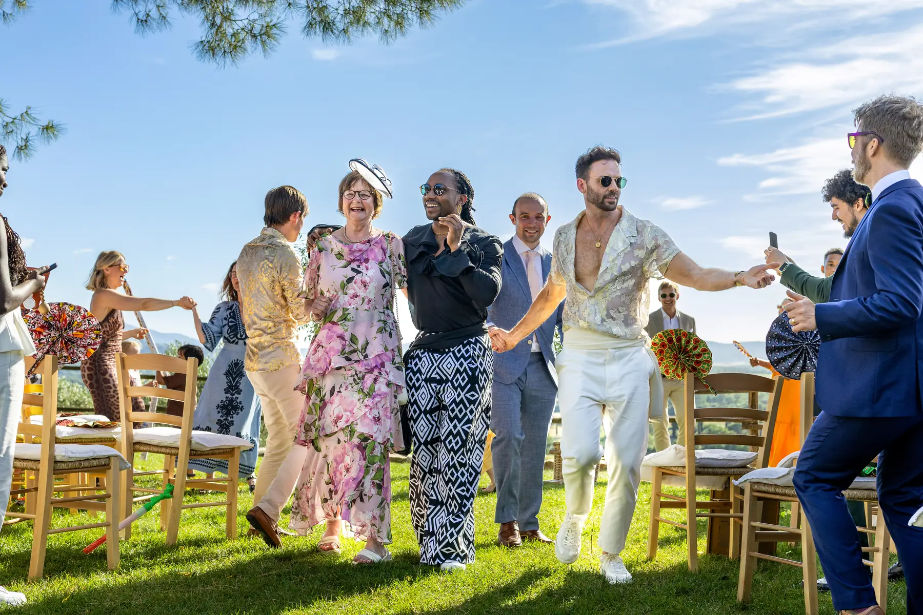 Two grooms walk back down the aisle with guests cheering at Conti di San Bonifacio Wine Resort in Tuscany, Italy.
